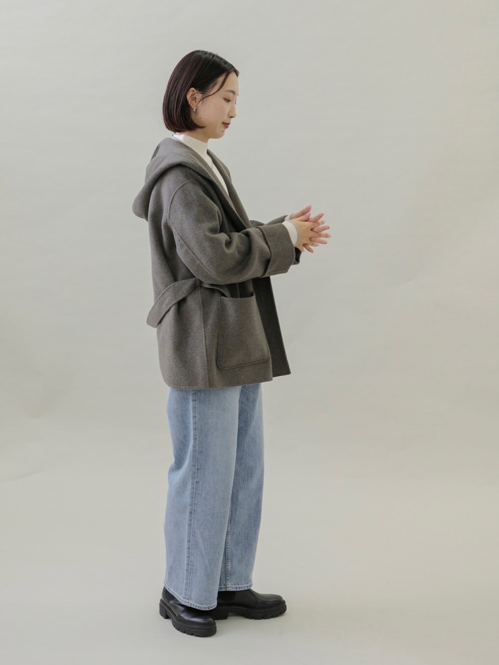 ブルー系のデニムパンツ、ブラック系のブーツ、グレー系のその他アウターを着用したレディースの秋コーディネートの3枚目の写真