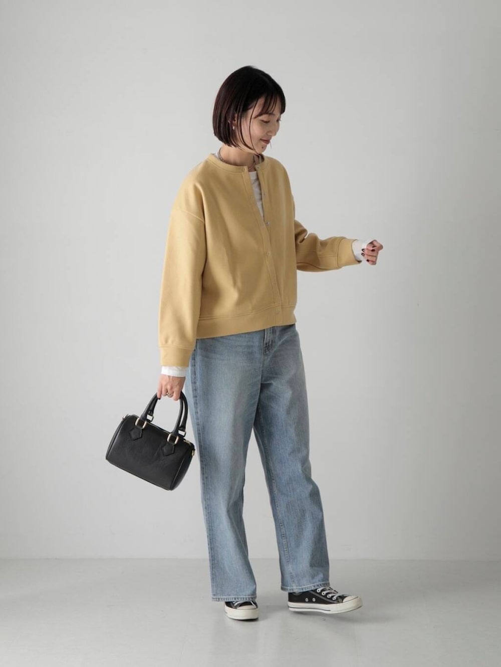 ブルー系のデニムパンツ、ホワイト系のTシャツ/カットソー、ブラック系のボストンバッグを着用したレディースの秋コーディネートの2枚目の写真