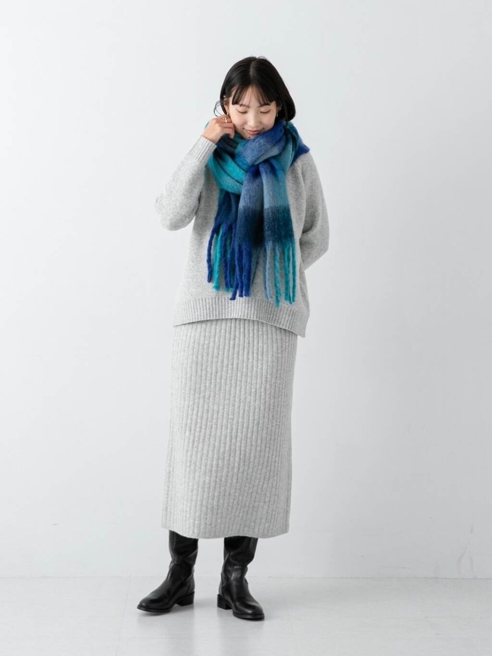 グレー系のワンピース、ブルー系のマフラーを着用したレディースの冬コーディネートの3枚目の写真