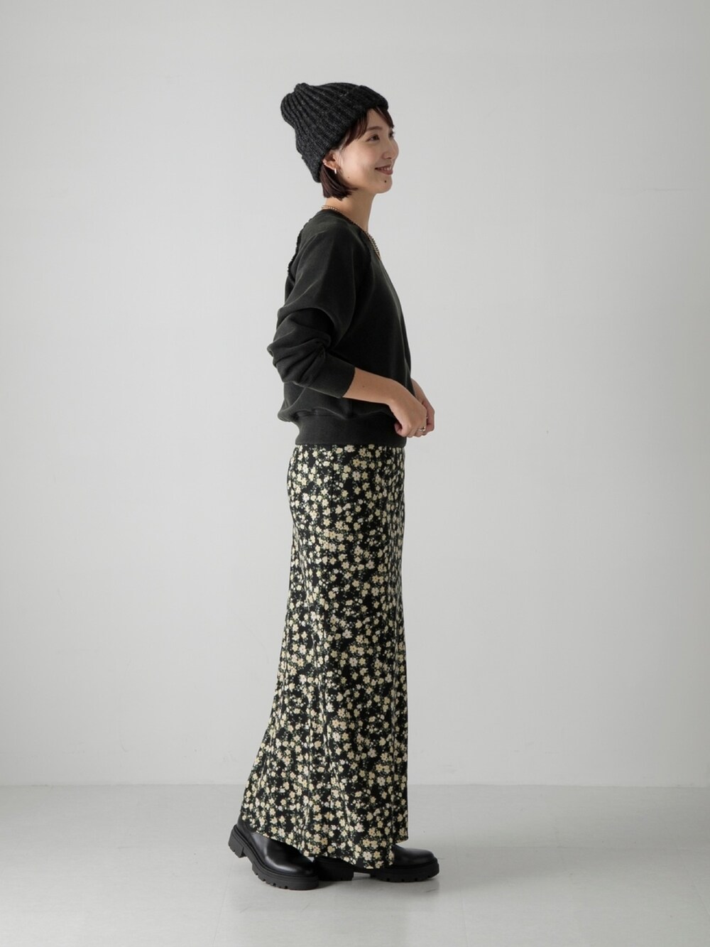 ブラック系のスウェット、ブラック系のスカート、ブラック系のブーツを着用したレディースの秋コーディネートの2枚目の写真