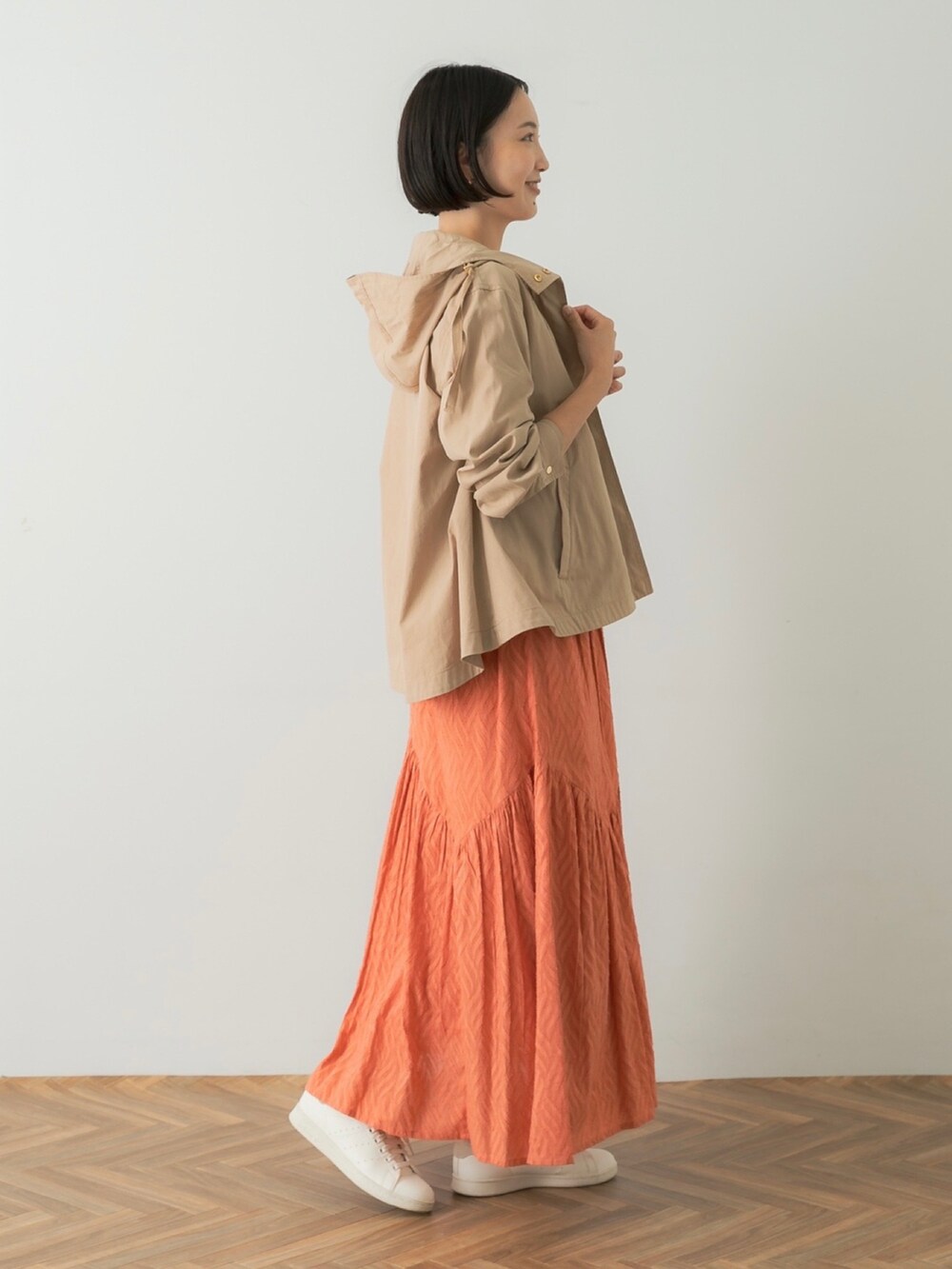 ホワイト系のTシャツ/カットソー、レッド系のスカート、ベージュ系のマウンテンパーカーを着用したレディースの夏コーディネートの2枚目の写真