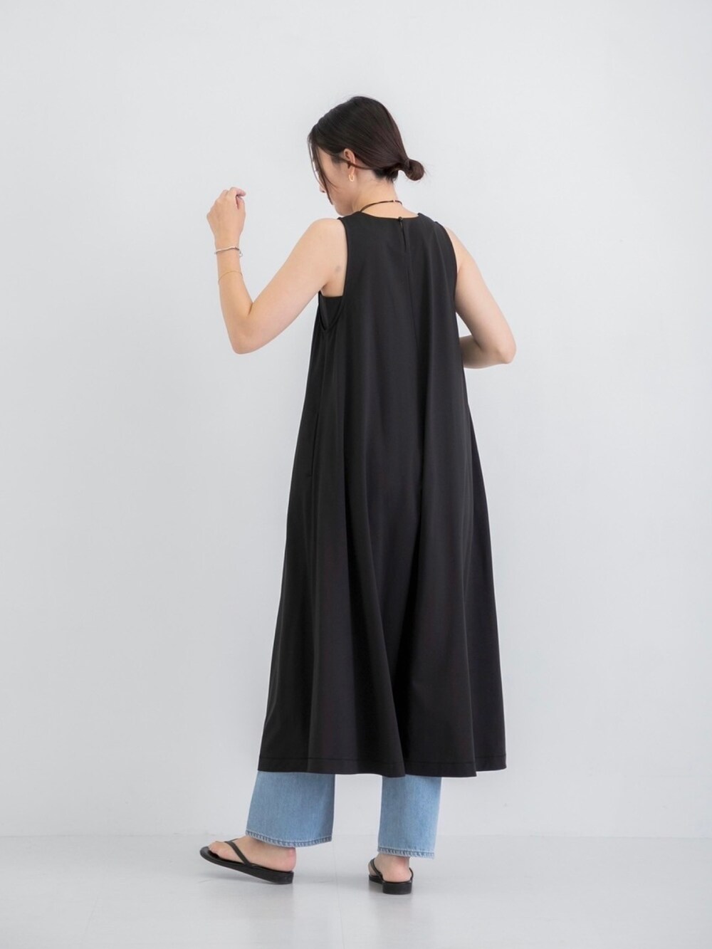 ブラック系のワンピース、ブルー系のデニムパンツ、シルバー系のネックレスを着用したレディースの夏コーディネートの2枚目の写真