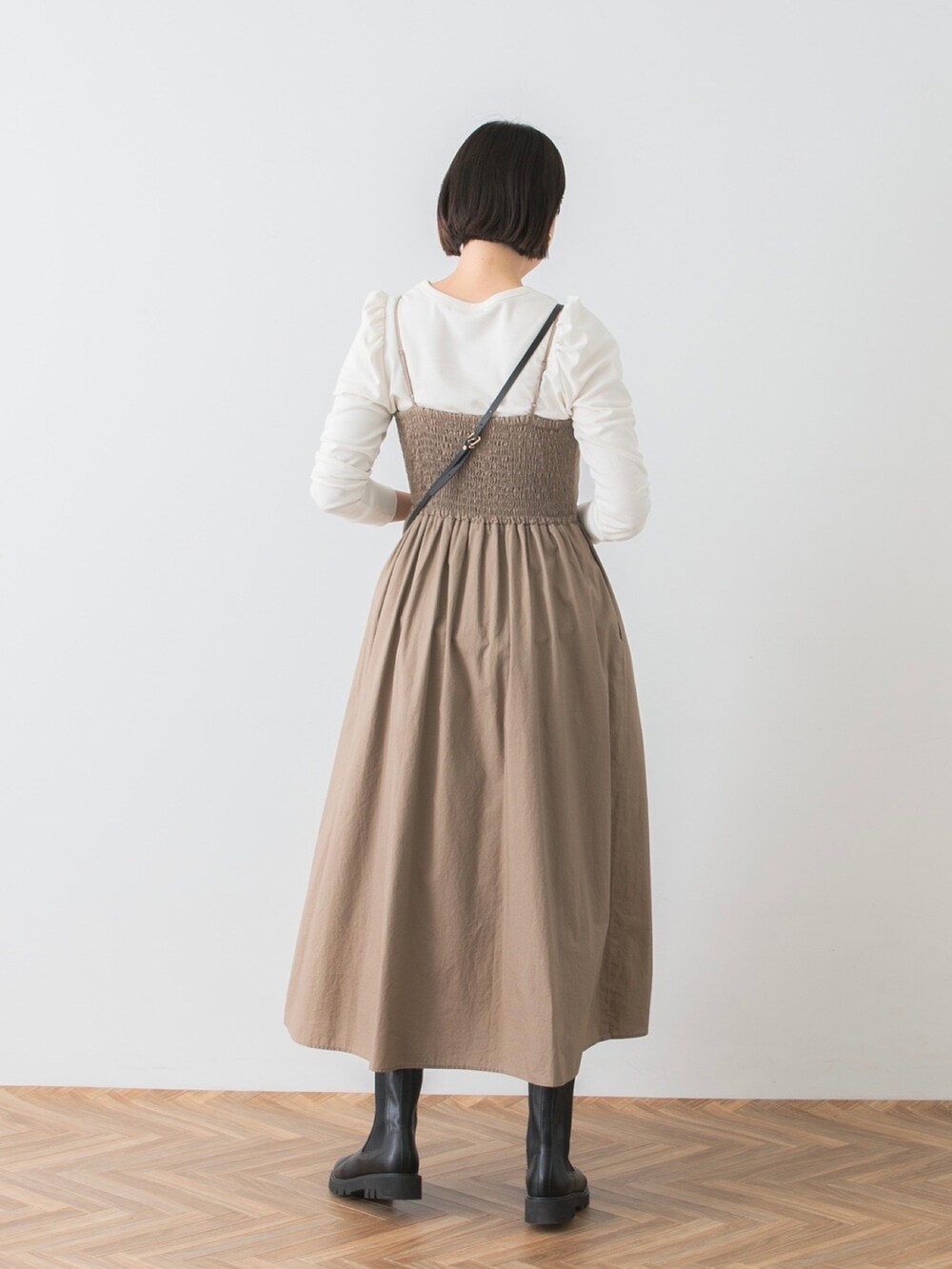 ベージュ系のワンピース、ホワイト系のTシャツ/カットソー、ブラック系のブーツを着用したレディースの秋コーディネートの3枚目の写真