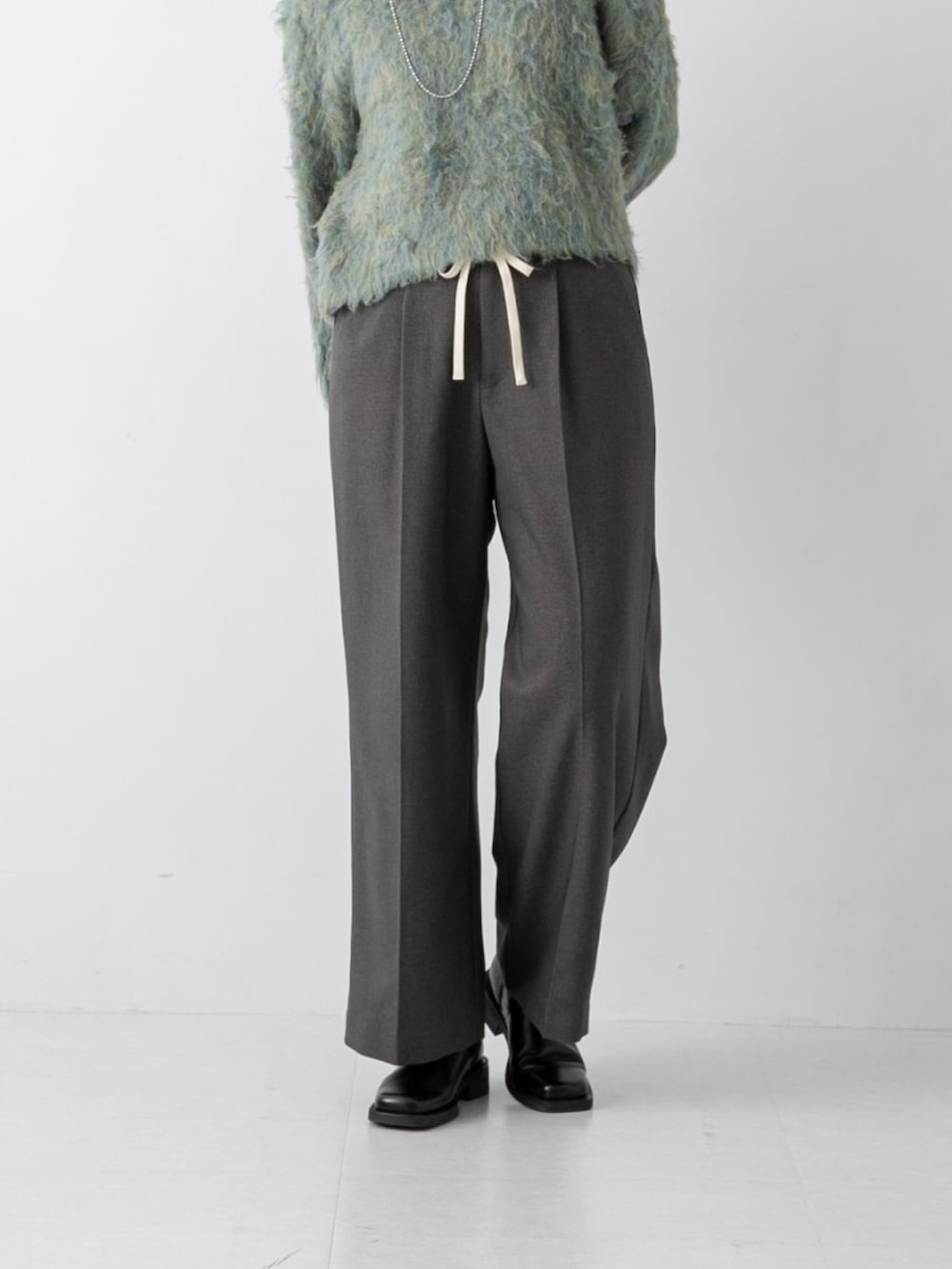 グリーン系のニット/セーター、グレー系のその他パンツを着用したレディースの冬コーディネートの3枚目の写真