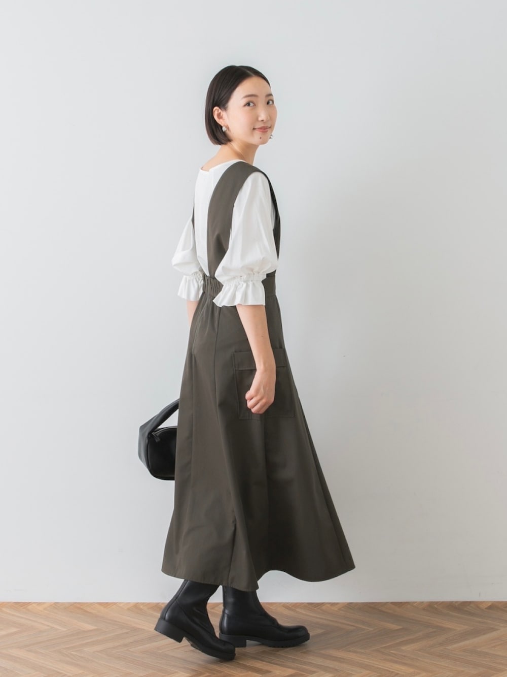 ブラック系のハンドバッグ、グリーン系のジャンパースカート、ホワイト系のTシャツ/カットソーを着用したレディースの夏コーディネートの2枚目の写真