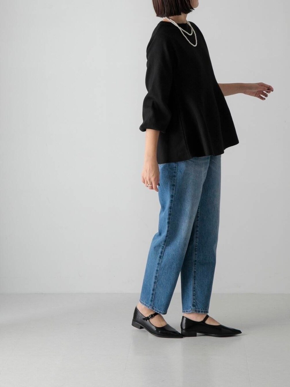 ブルー系のデニムパンツ、ブラック系のその他シューズ、ブラック系のニット/セーターを着用したレディースの秋コーディネートの2枚目の写真