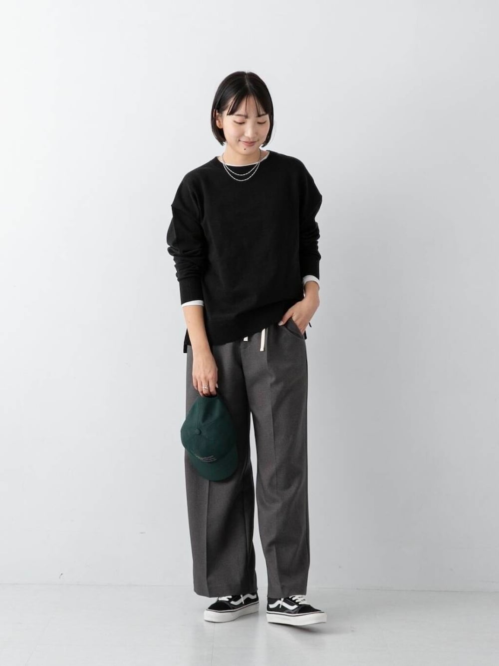 ブラック系のニット/セーター、グレー系のその他パンツ、グリーン系のキャップを着用したレディースの冬コーディネートの2枚目の写真