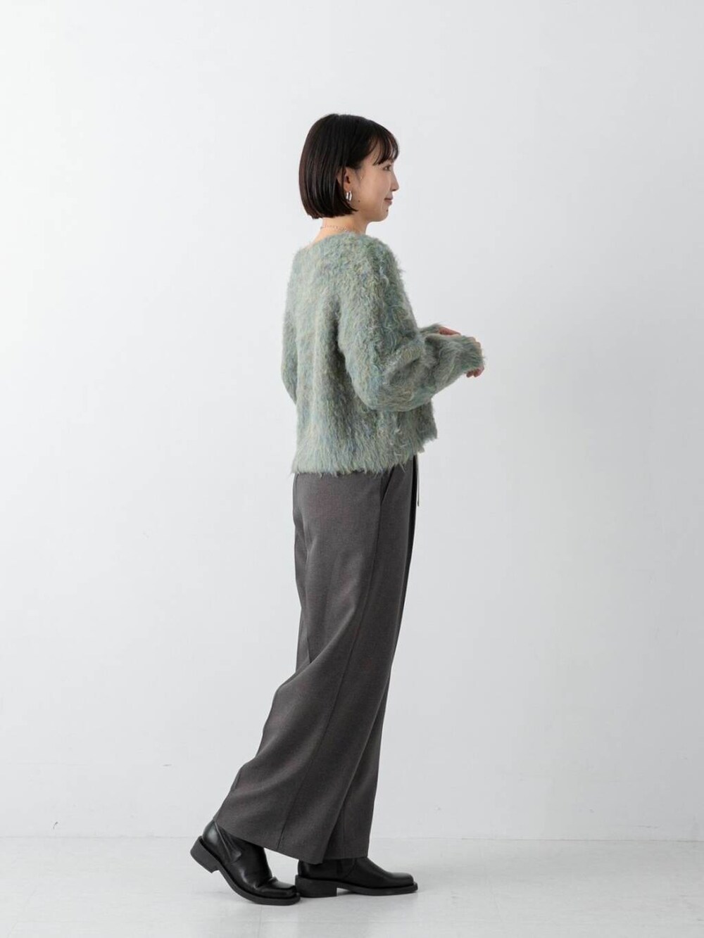 グリーン系のニット/セーター、グレー系のその他パンツを着用したレディースの冬コーディネートの2枚目の写真