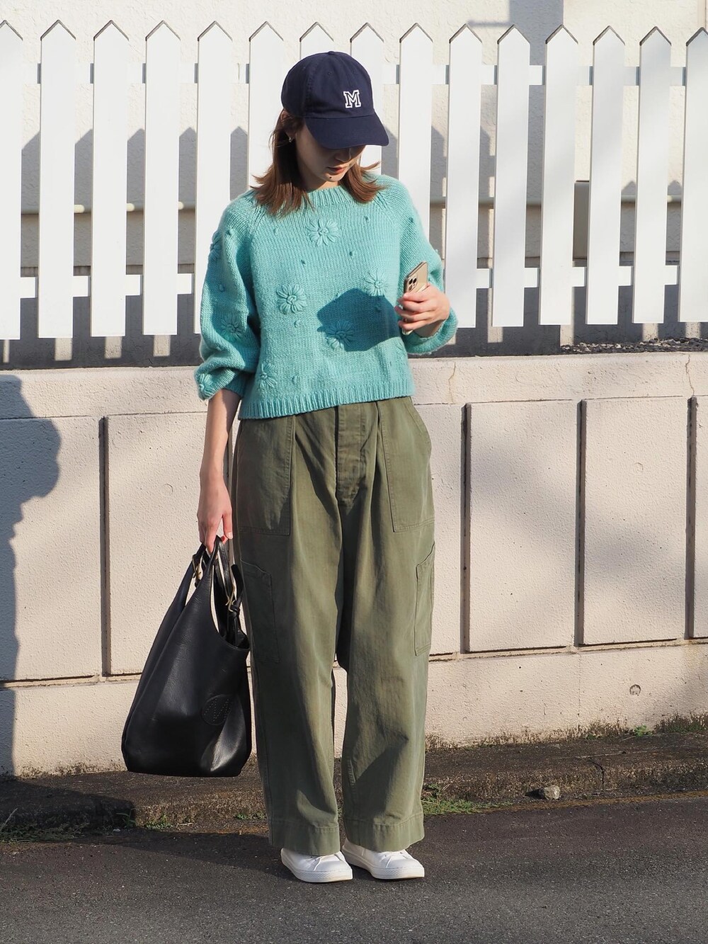 ホワイト系のスニーカー、ブルー系のキャップを着用したレディースの秋コーディネートの2枚目の写真