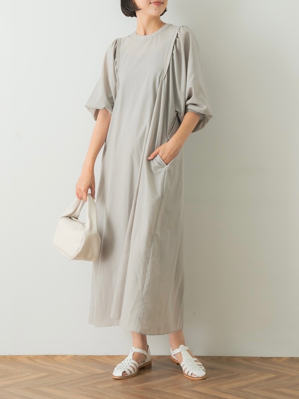 グレー系のワンピース、ホワイト系のハンドバッグ、ホワイト系のサンダルを着用したレディースの夏コーディネートの4枚目の写真