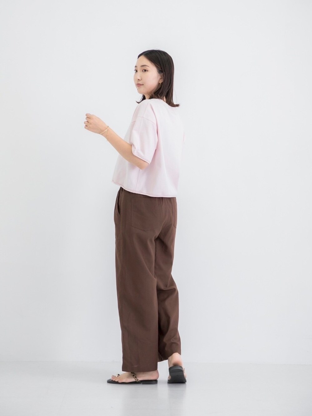 ピンク系のTシャツ/カットソー、ブラウン系のその他パンツ、その他のサンダルを着用したレディースの夏コーディネートの2枚目の写真