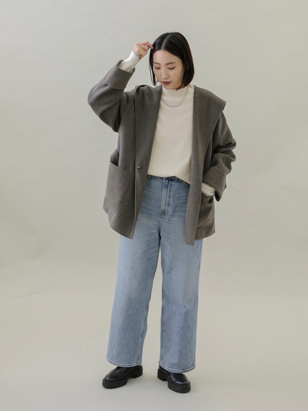 ブルー系のデニムパンツ、ブラック系のブーツ、グレー系のその他アウターを着用したレディースの秋コーディネートの5枚目の写真