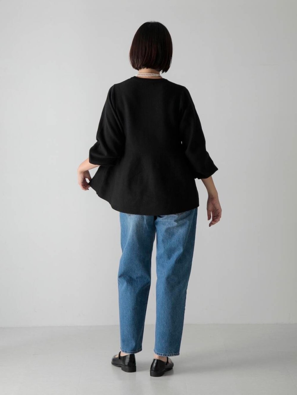 ブルー系のデニムパンツ、ブラック系のその他シューズ、ブラック系のニット/セーターを着用したレディースの秋コーディネートの3枚目の写真