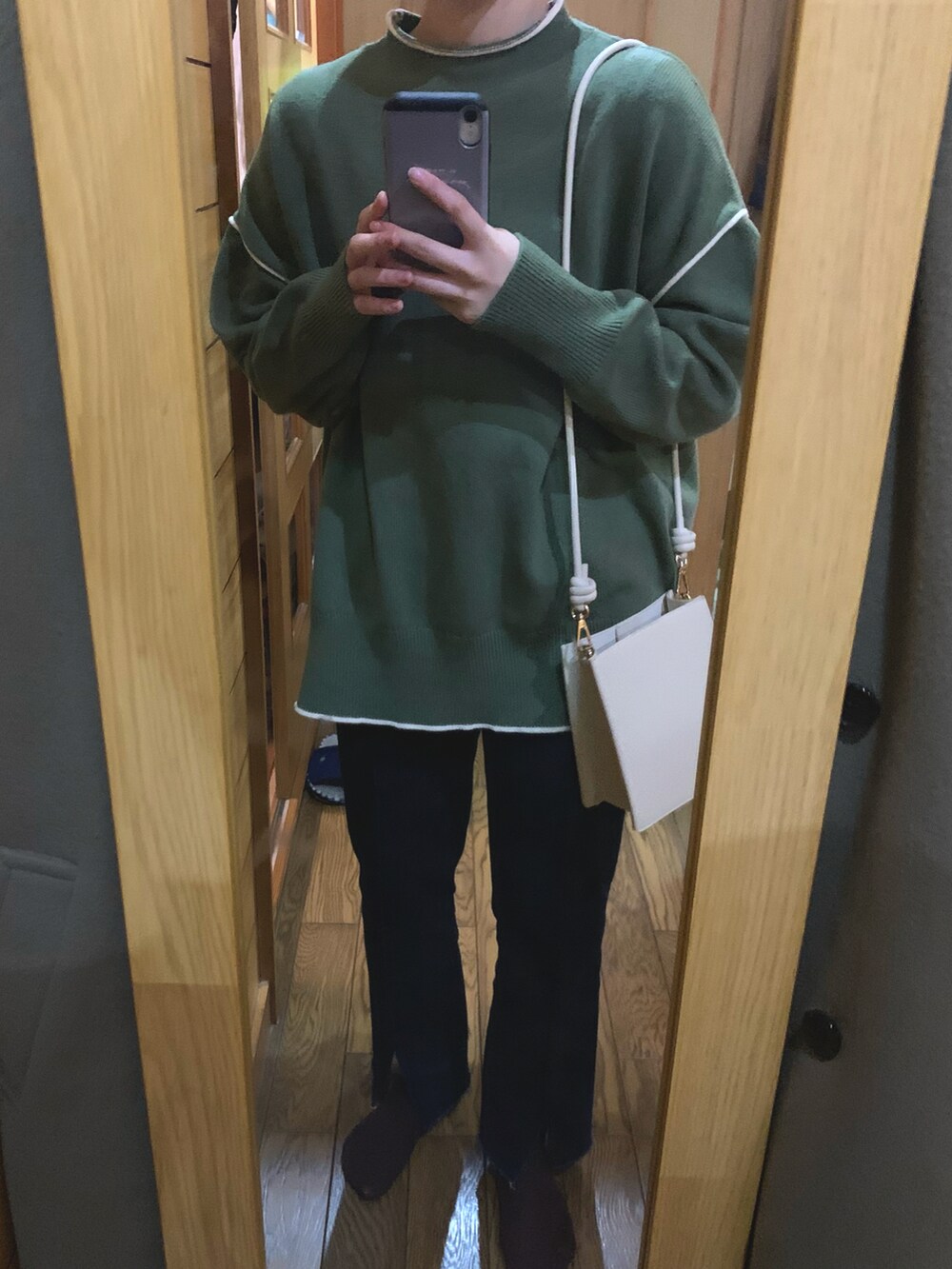 ベージュ系のショルダーバッグ、ブルー系のデニムパンツ、グリーン系のニット/セーターを着用したレディースの冬コーディネートの2枚目の写真