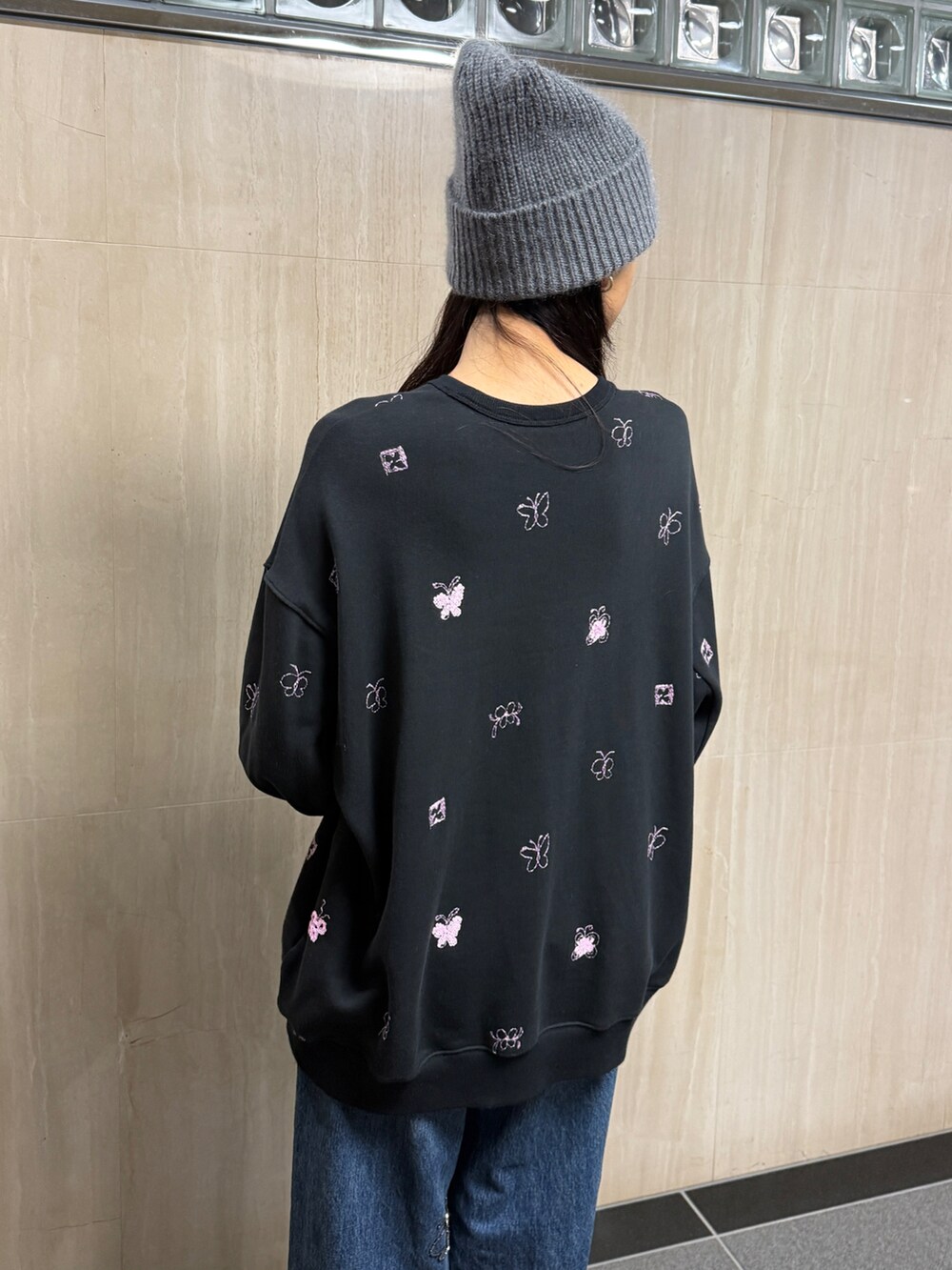 ブラック系のスウェット、ブルー系のデニムパンツ、グレー系のニットキャップ/ビーニーを着用したレディースの冬コーディネートの2枚目の写真