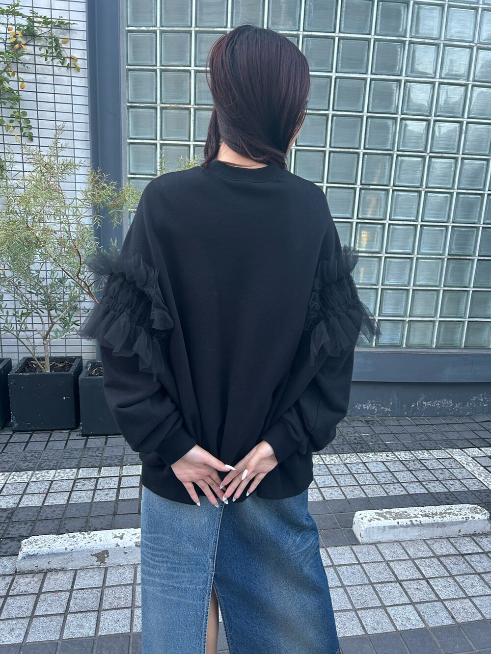 ブラック系のトップス、ブルー系のデニムスカートを着用したレディースの秋コーディネートの2枚目の写真