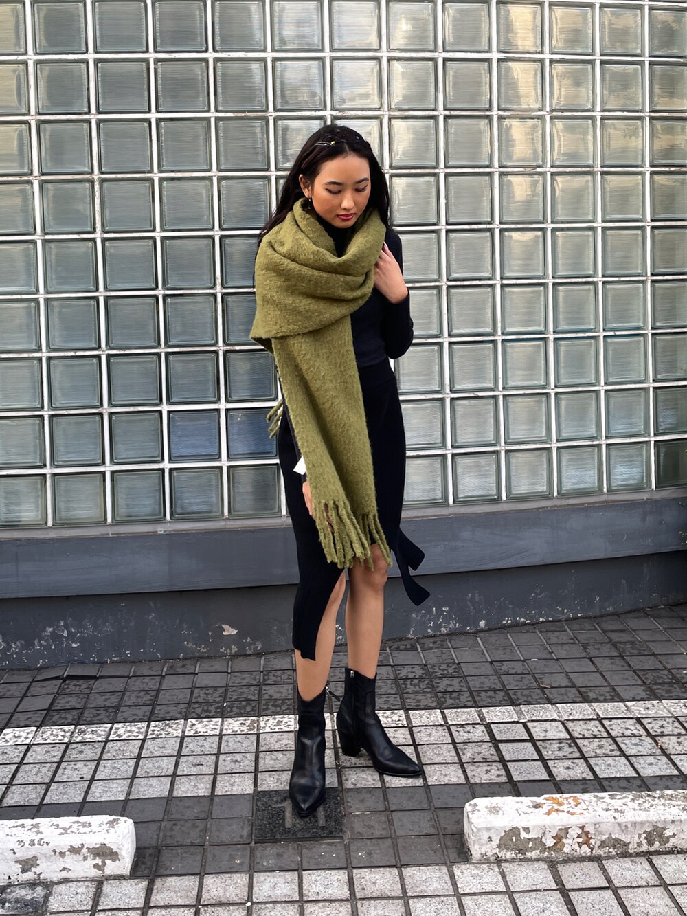 ブラック系のスカート、ブラック系のニット/セーター、グリーン系のマフラーを着用したレディースの冬コーディネートの4枚目の写真