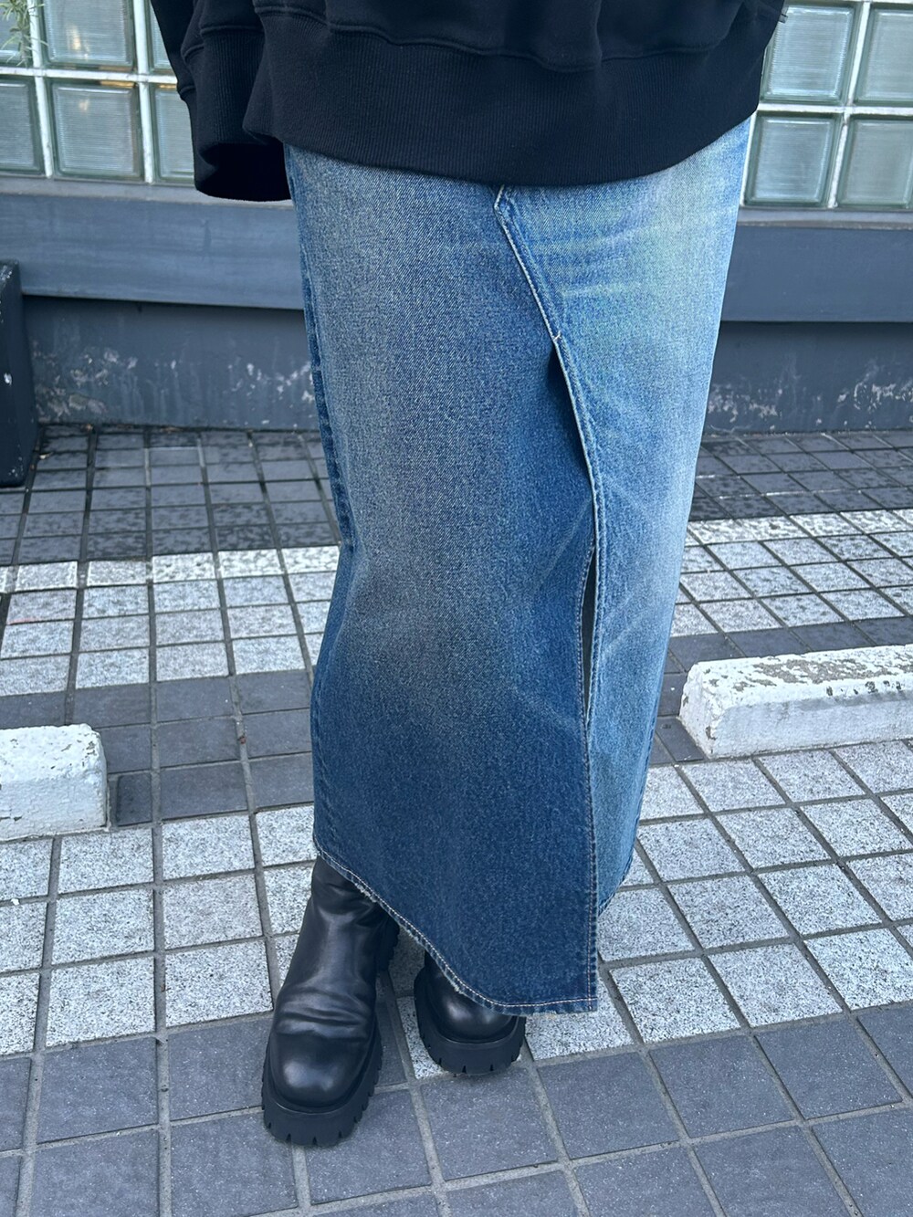 ブラック系のトップス、ブルー系のデニムスカートを着用したレディースの秋コーディネートの3枚目の写真