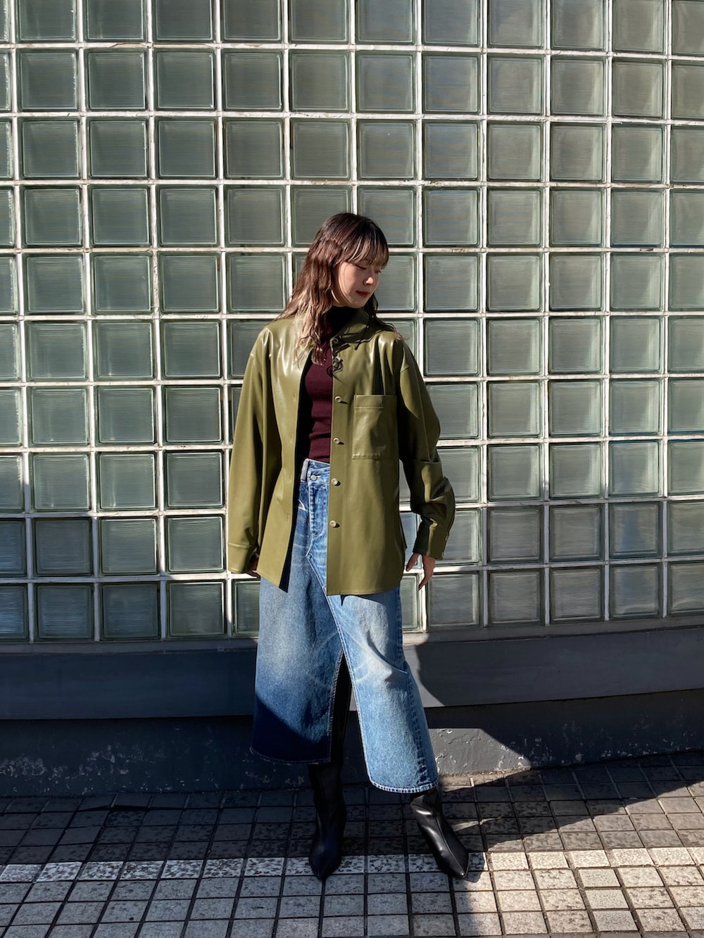 レッド系のニット/セーター、グリーン系のブルゾン、ブルー系のデニムスカートを着用したレディースの秋コーディネートの3枚目の写真