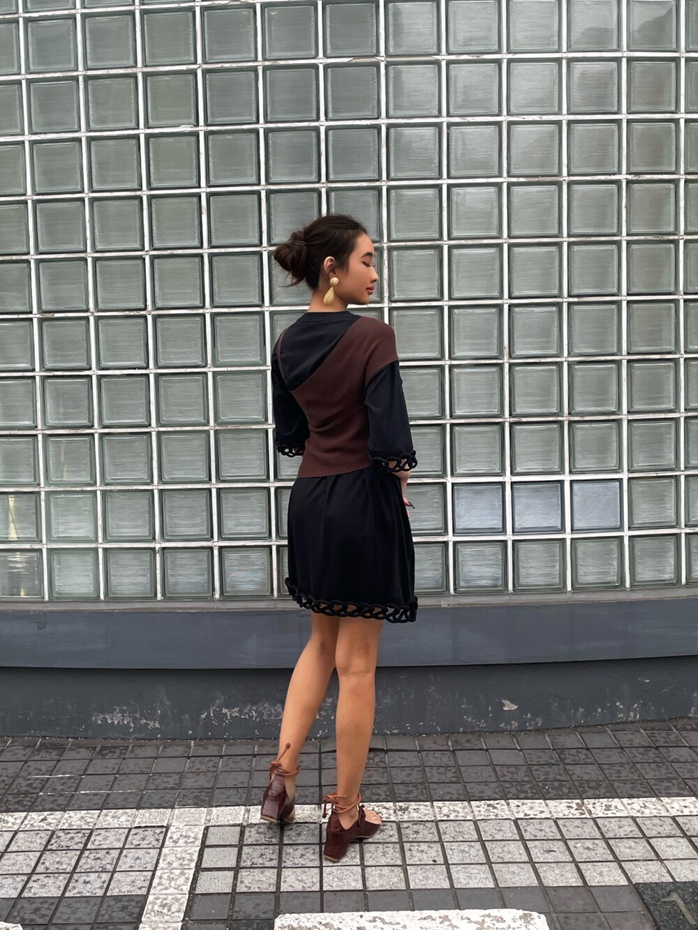 ブラウン系のニット/セーター、ブラック系のワンピース、ブラウン系のサンダルを着用したレディースの夏コーディネートの2枚目の写真
