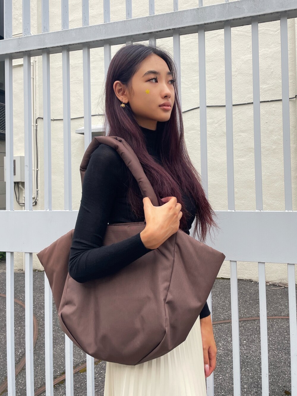 ブラウン系のトートバッグ、ホワイト系のスカート、ブラック系のニット/セーターを着用したレディースの秋コーディネートの3枚目の写真