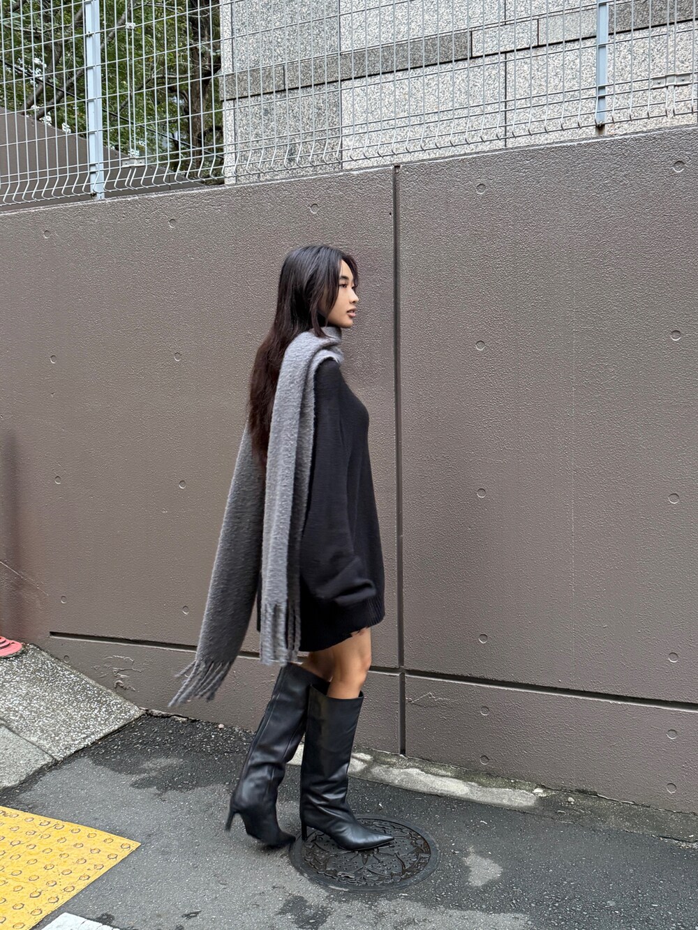 ブラック系のニット/セーター、ブラック系のショルダーバッグ、グレー系のストール/ショールを着用したレディースの冬コーディネートの2枚目の写真