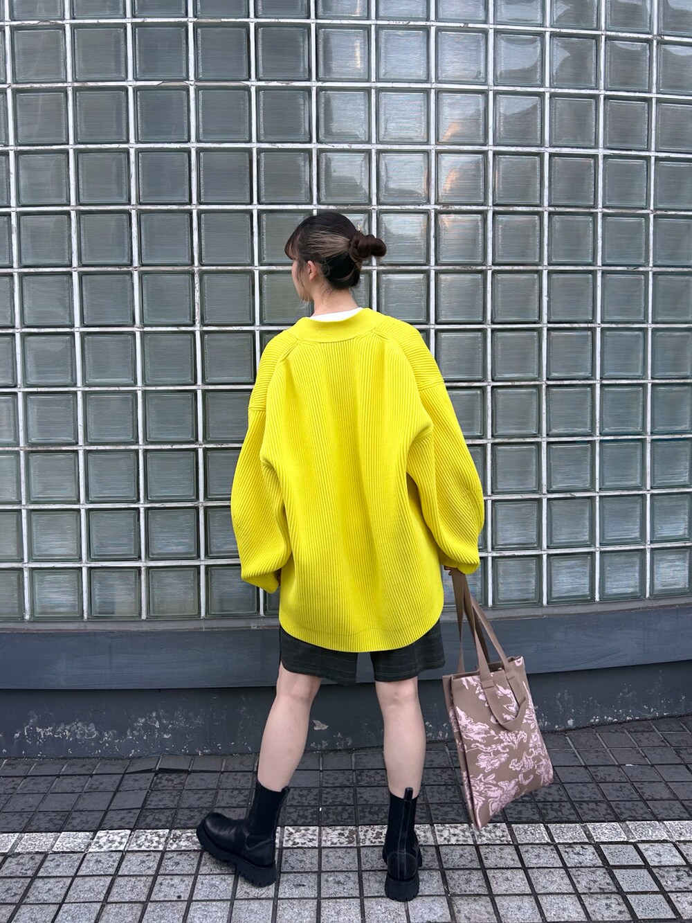 イエロー系のカーディガン/ボレロ、ホワイト系のニット/セーター、ベージュ系のトートバッグを着用したレディースの冬コーディネートの2枚目の写真