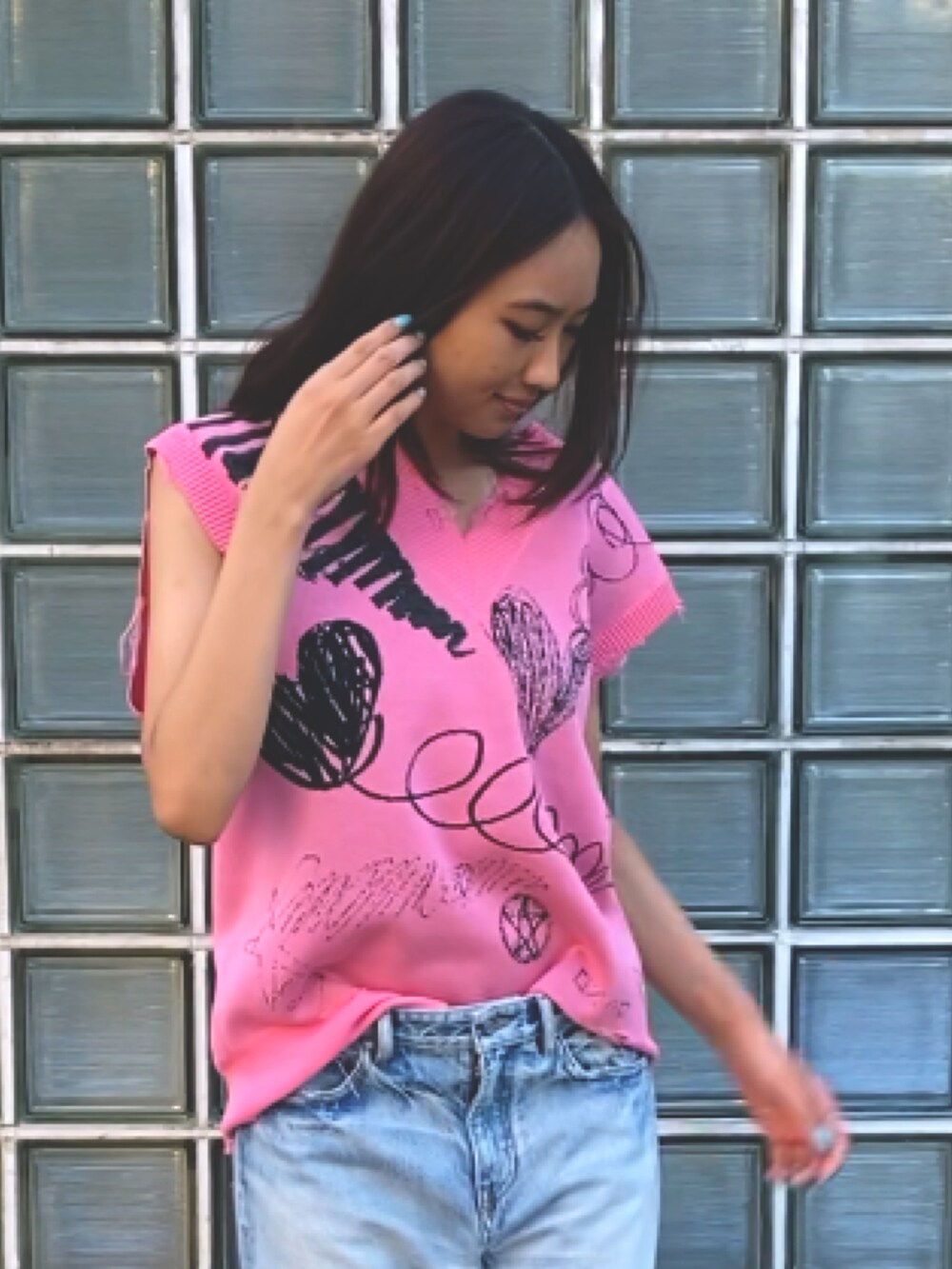 ピンク系のベスト、ブルー系のデニムパンツを着用したレディースの夏コーディネートの3枚目の写真