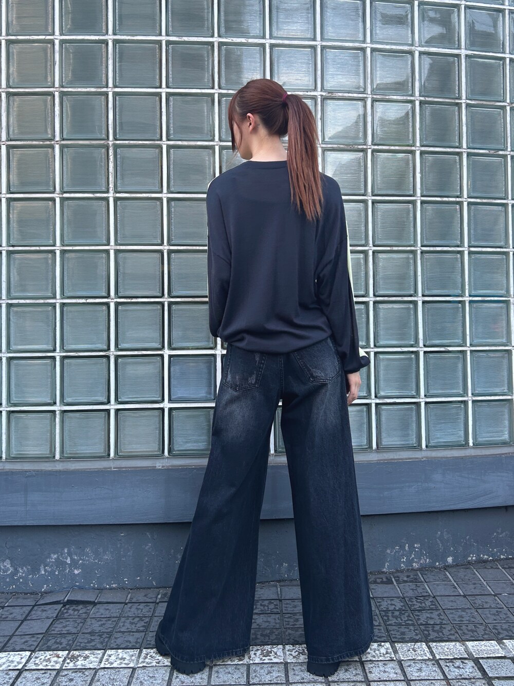 イエロー系のトップス、ブラック系のデニムパンツを着用したレディースの夏コーディネートの2枚目の写真