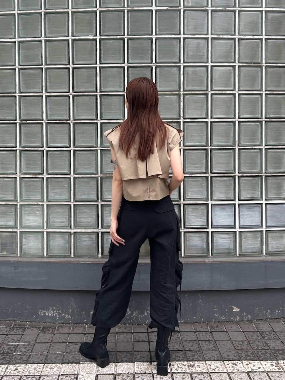 ベージュ系のベスト、ブラック系のデニムパンツを着用したレディースの夏コーディネートの2枚目の写真