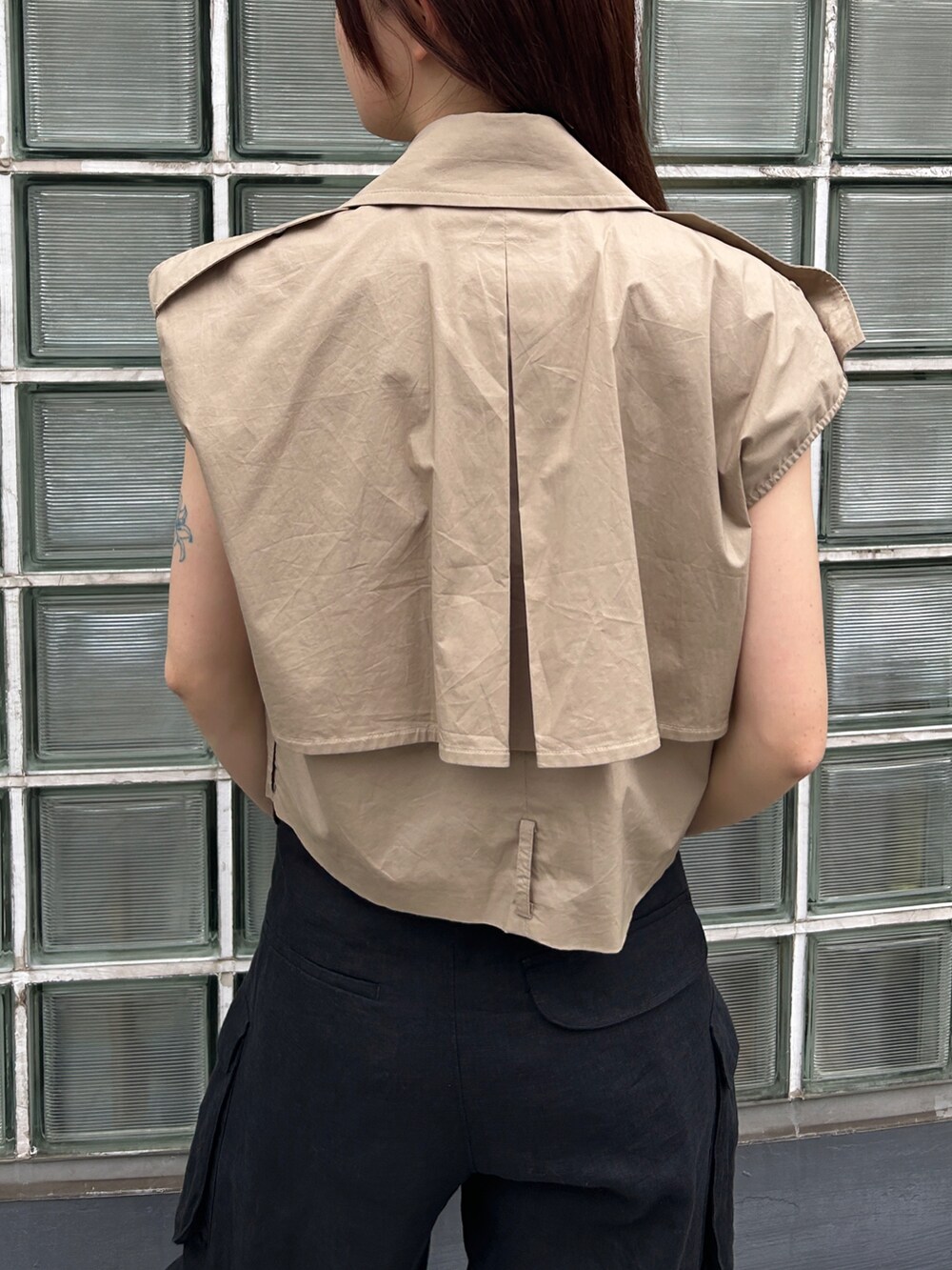 ベージュ系のベスト、ブラック系のデニムパンツを着用したレディースの夏コーディネートの4枚目の写真