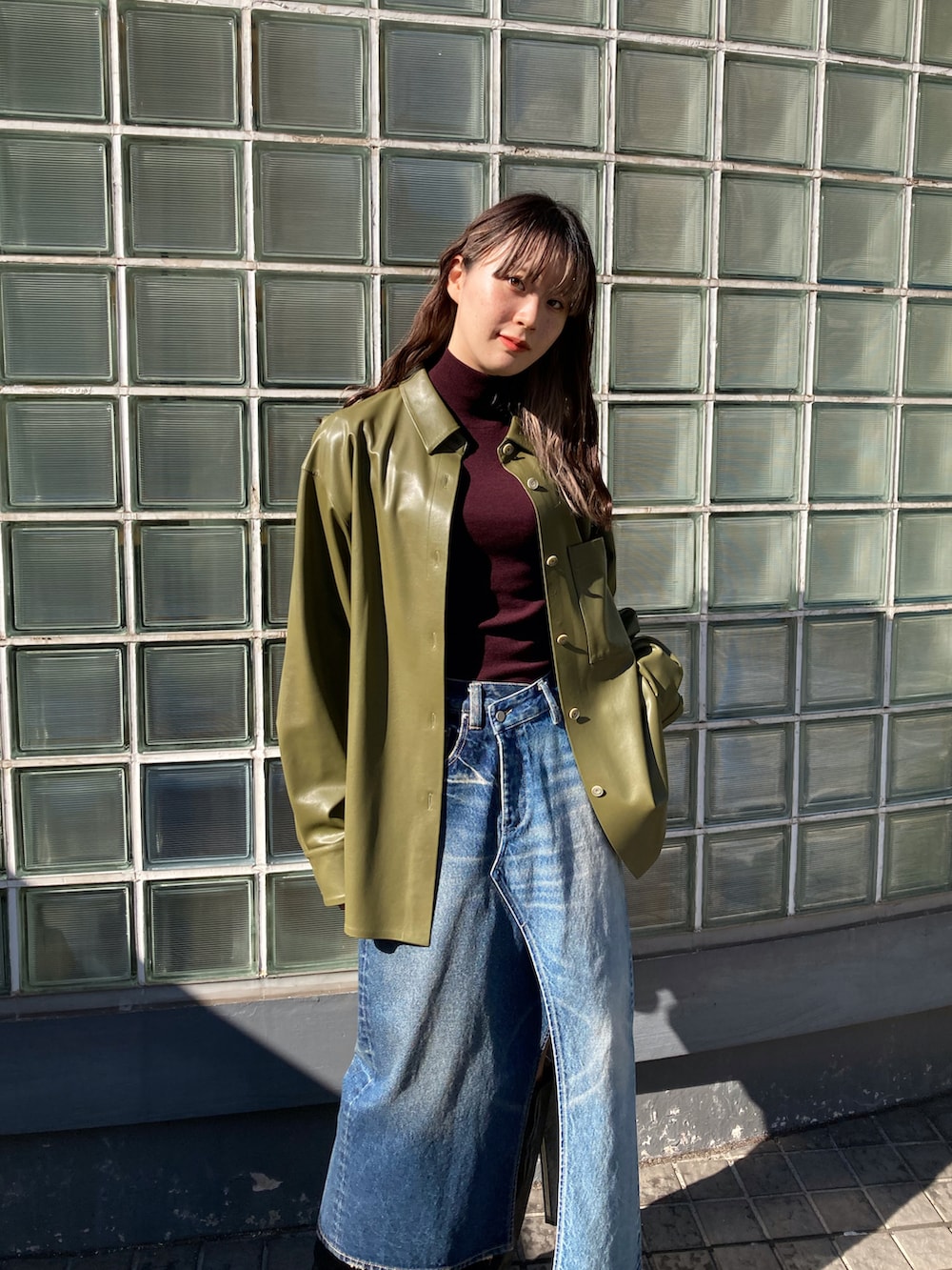 レッド系のニット/セーター、グリーン系のブルゾン、ブルー系のデニムスカートを着用したレディースの秋コーディネートの2枚目の写真