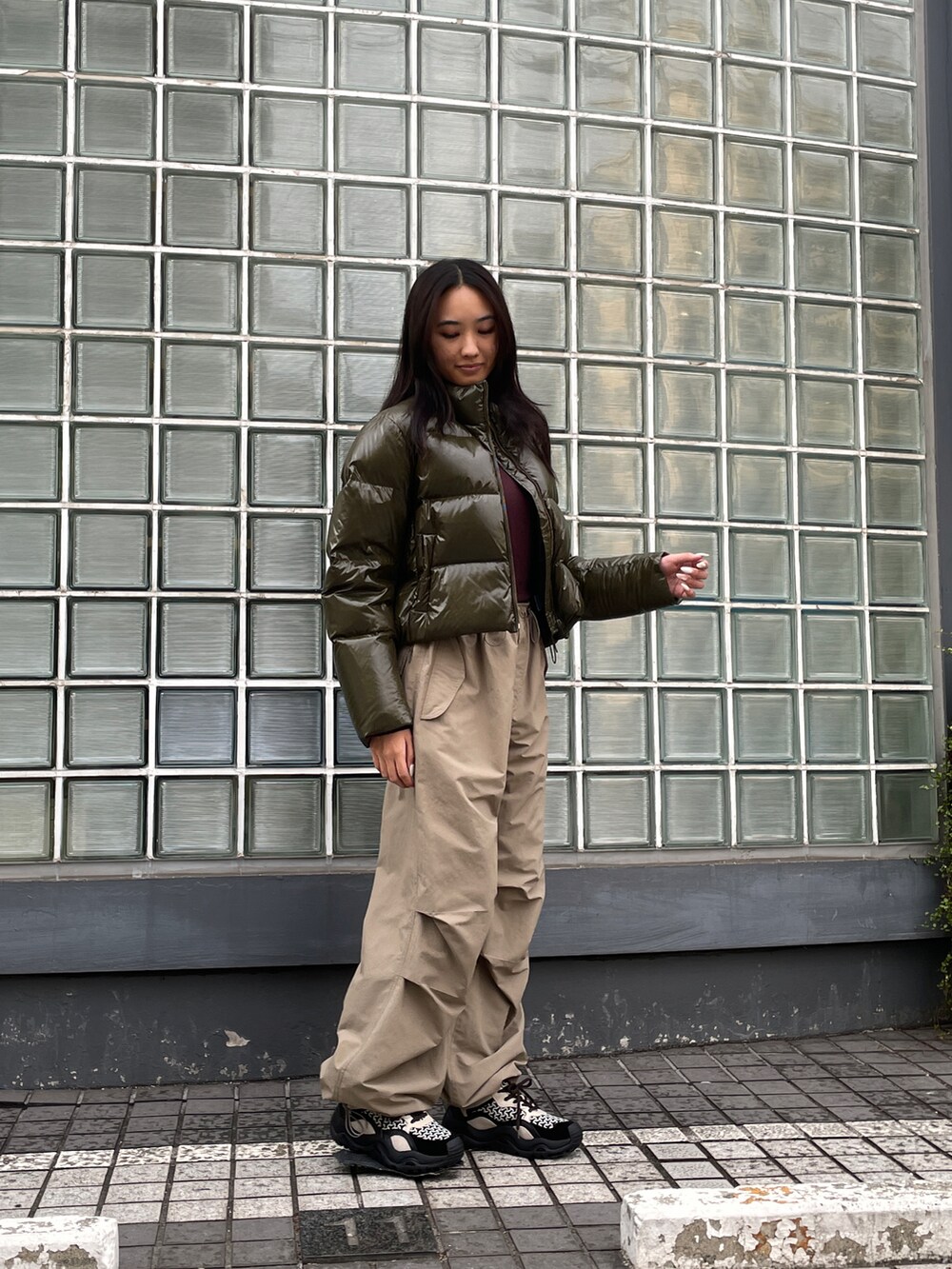 グリーン系のダウンジャケット/コート、ベージュ系のその他パンツ、ブラック系のスニーカーを着用したレディースの秋コーディネートの2枚目の写真