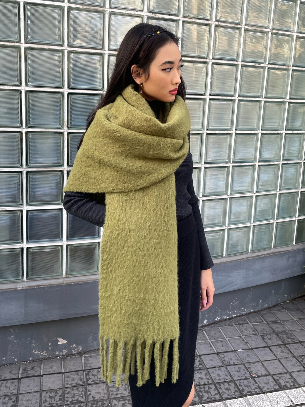 ブラック系のスカート、ブラック系のニット/セーター、グリーン系のマフラーを着用したレディースの冬コーディネートの2枚目の写真