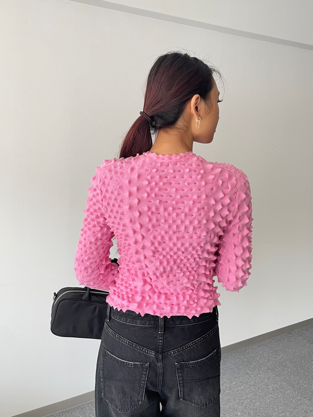 ブラック系のデニムパンツ、ピンク系のニット/セーター、ブラック系のショルダーバッグを着用したレディースの秋コーディネートの3枚目の写真