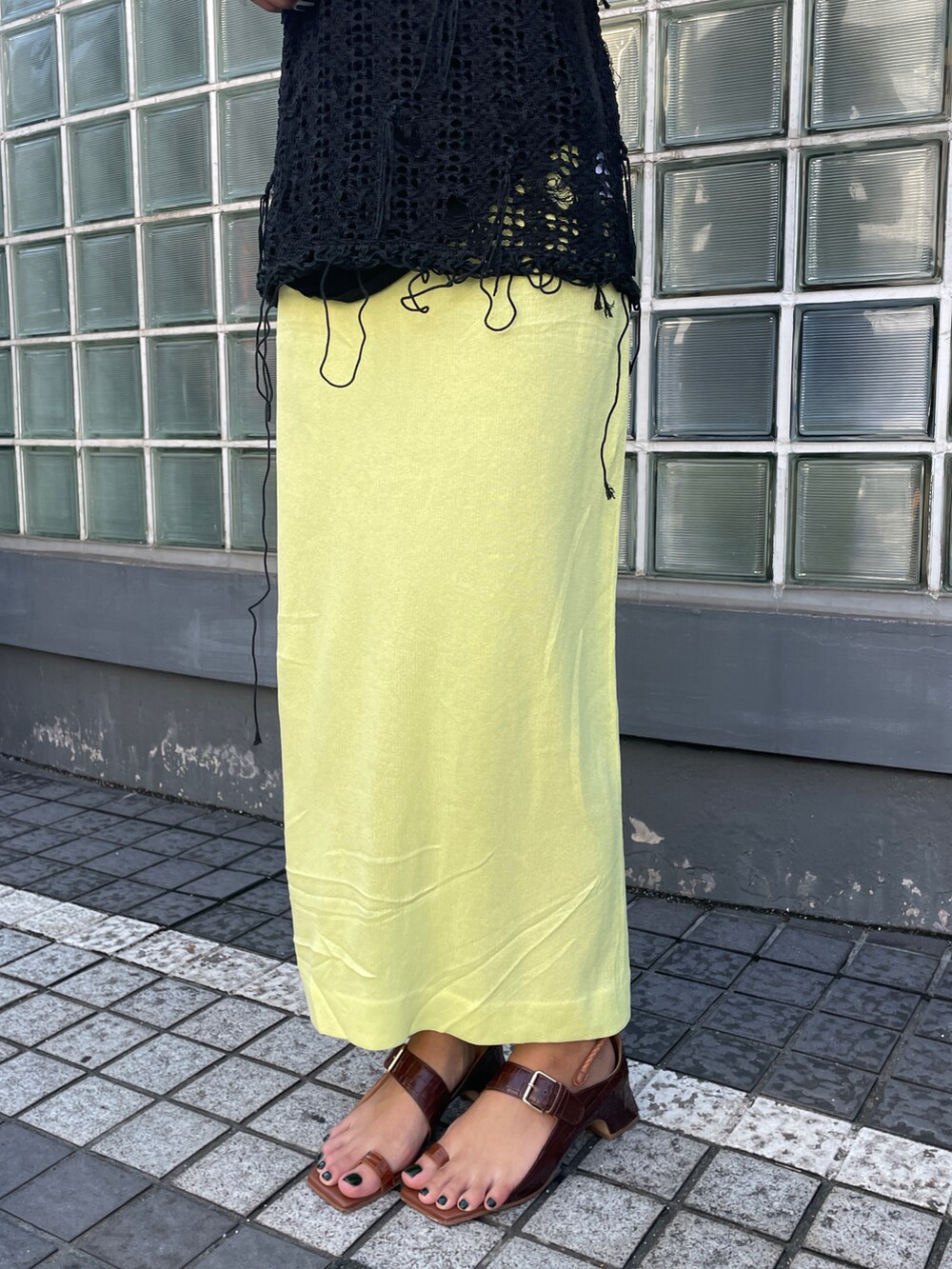 ブラック系のニット/セーター、イエロー系のスカートを着用したレディースの夏コーディネートの3枚目の写真