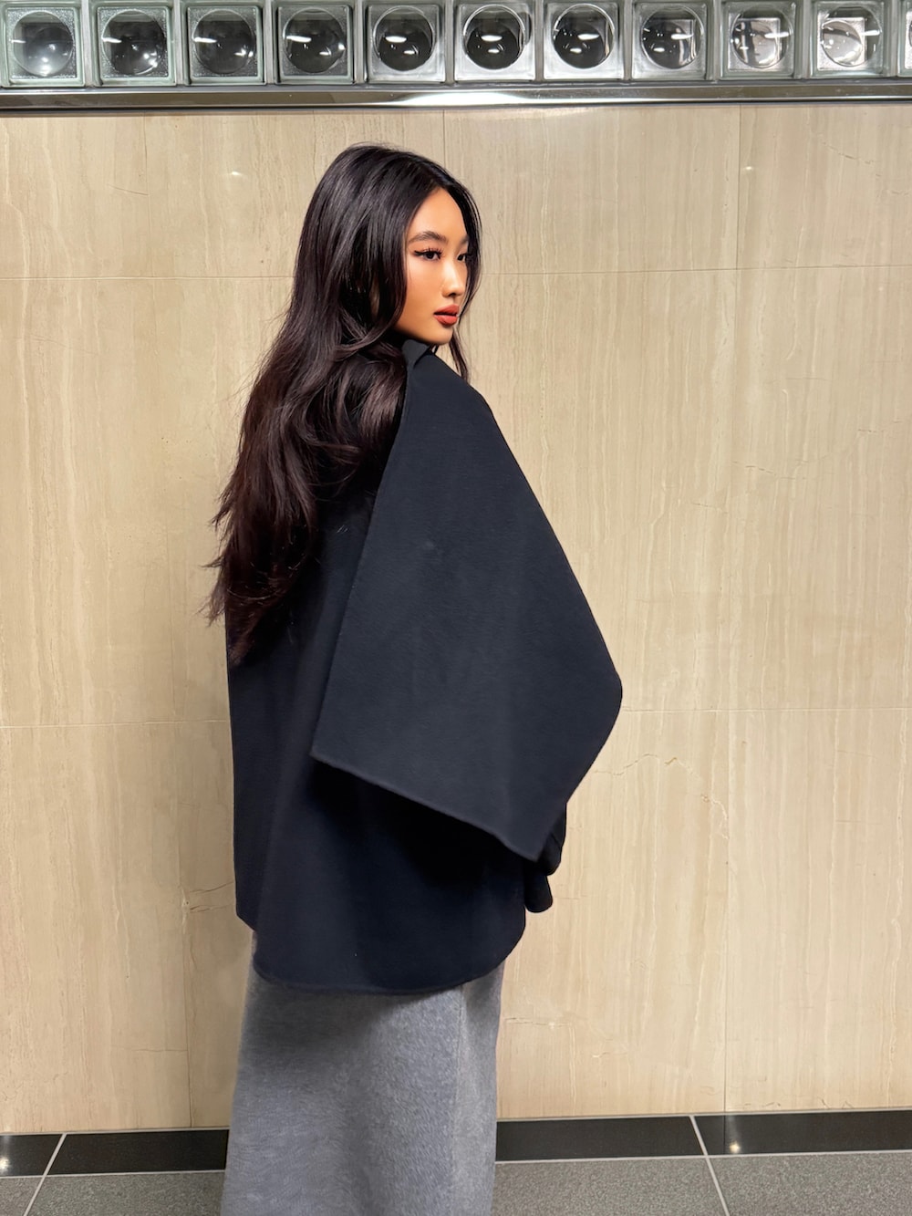 ブラック系のその他アウター、グレー系のスカートを着用したレディースの冬コーディネートの4枚目の写真