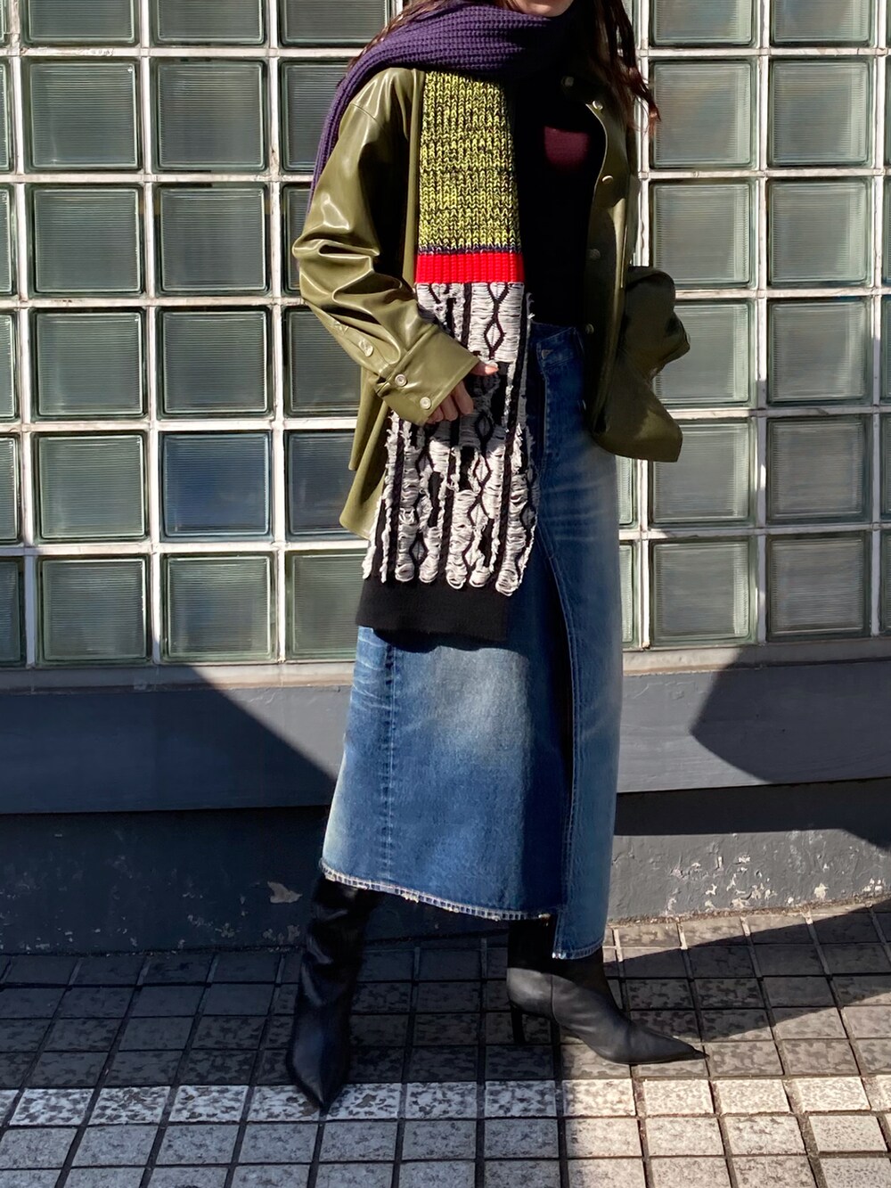 グリーン系のブルゾン、ブルー系のデニムスカート、パープル系のマフラーを着用したレディースの冬コーディネートの3枚目の写真