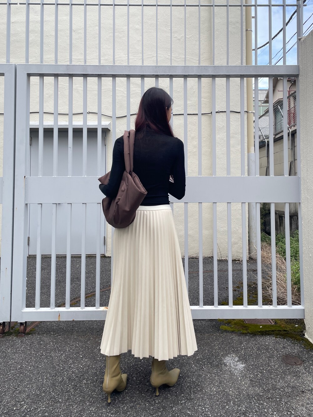 ブラウン系のトートバッグ、ホワイト系のスカート、ブラック系のニット/セーターを着用したレディースの秋コーディネートの4枚目の写真