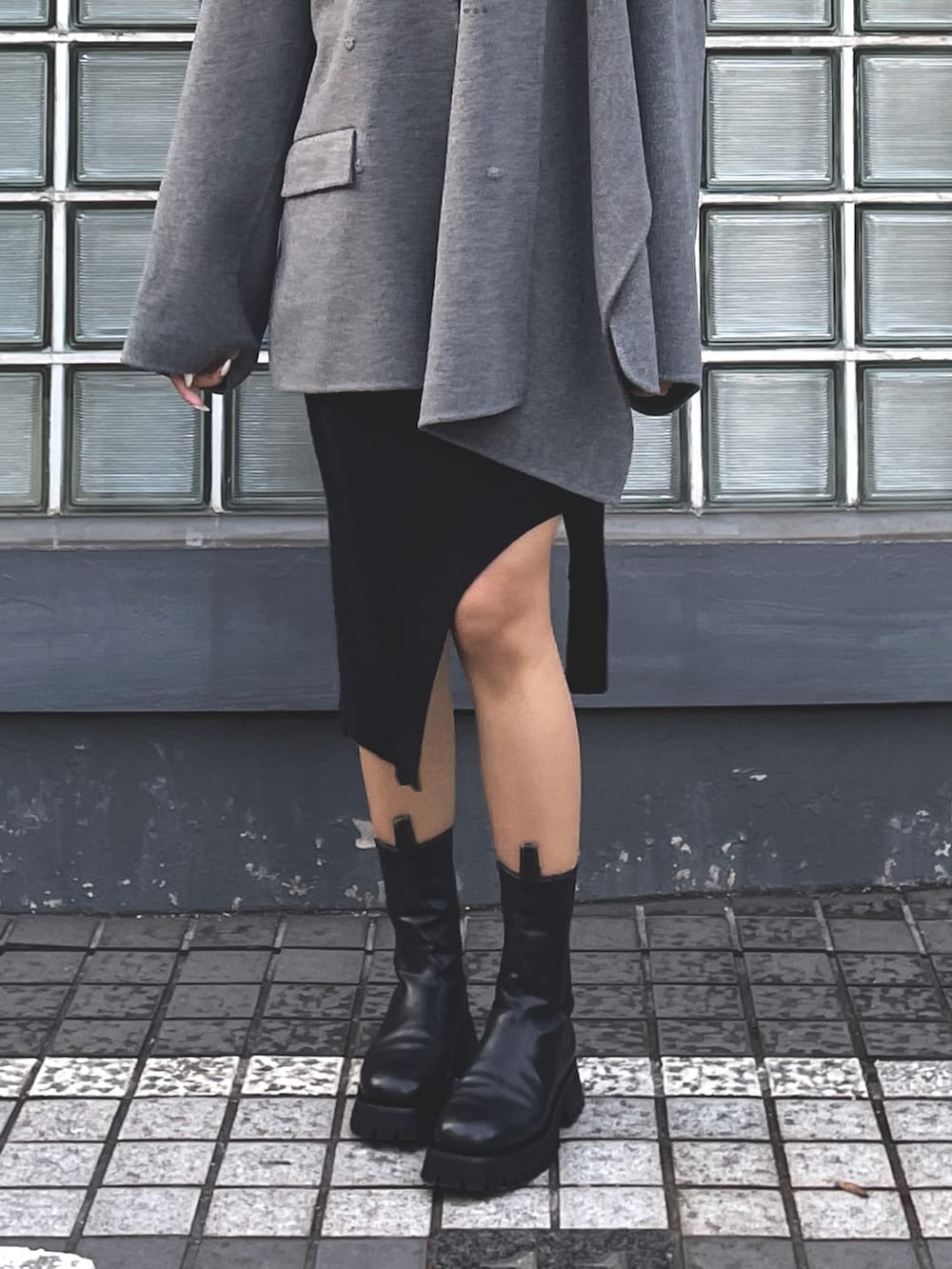 グレー系のその他アウター、ブラック系のスカート、ブラック系のブーツを着用したレディースの冬コーディネートの4枚目の写真