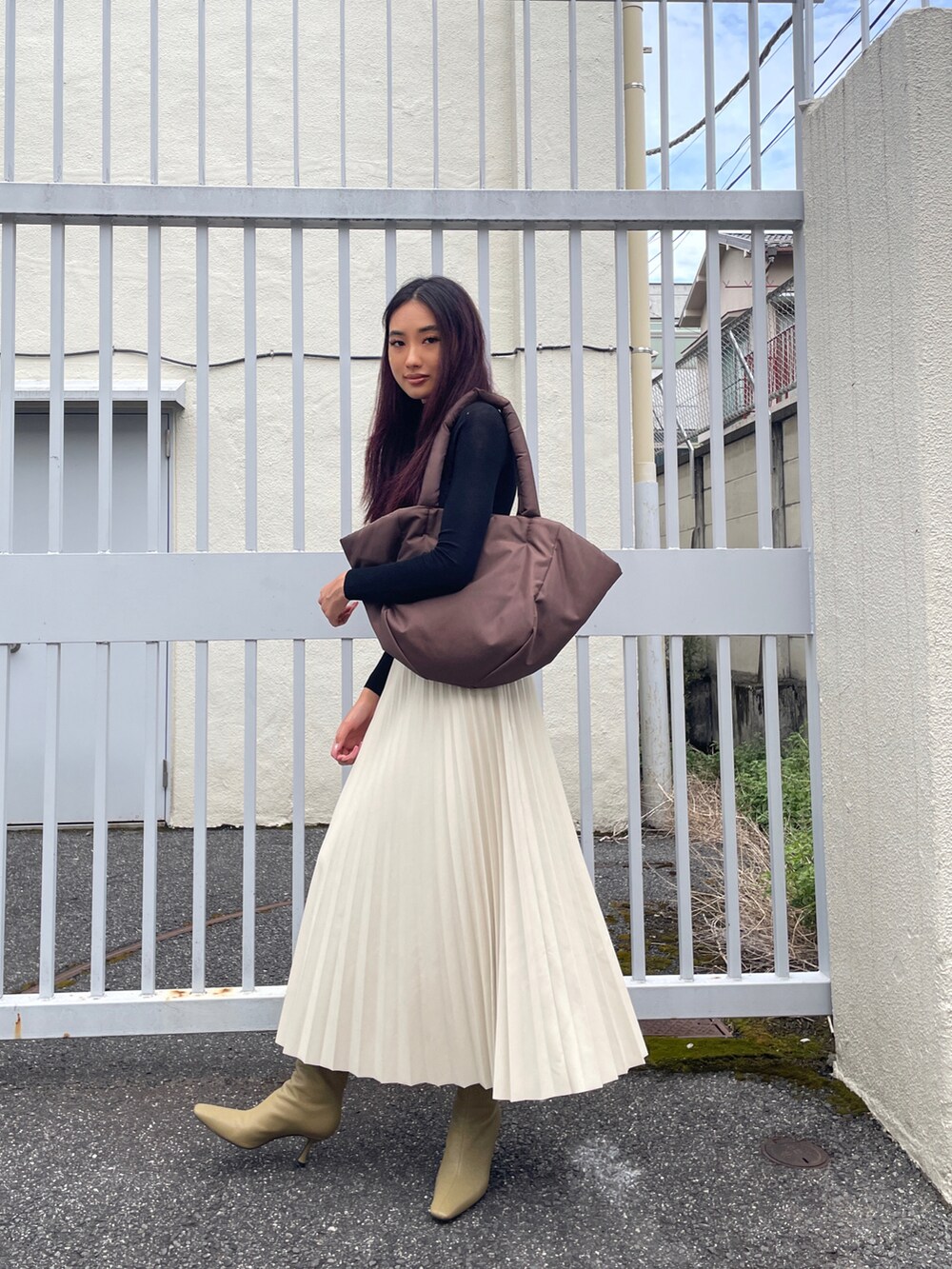 ブラウン系のトートバッグ、ホワイト系のスカート、ブラック系のニット/セーターを着用したレディースの秋コーディネートの2枚目の写真