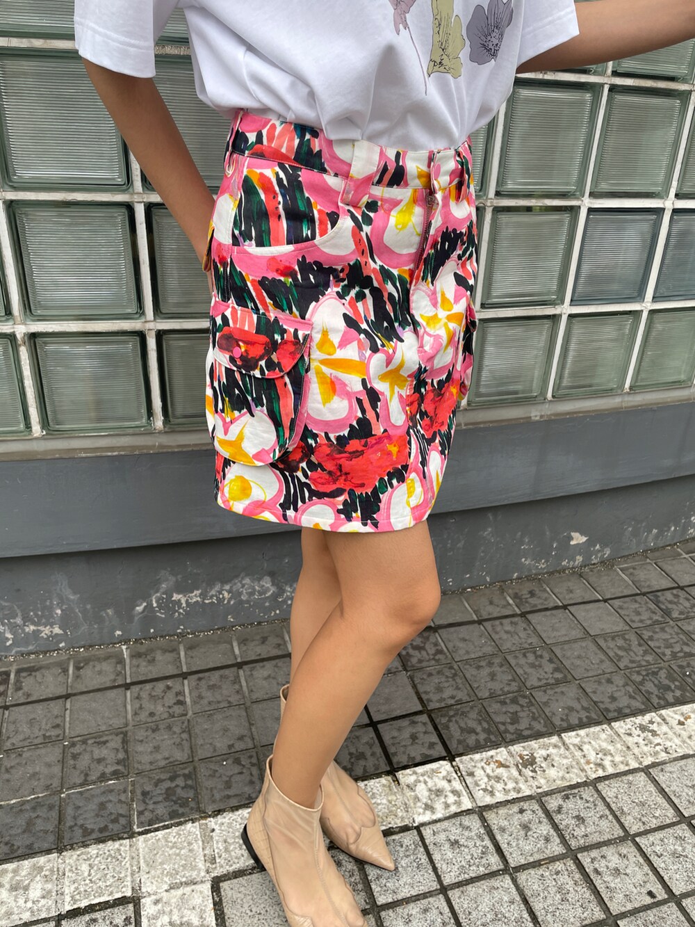 ホワイト系のトップス、ピンク系のスカート、ブラウン系のサンダルを着用したレディースの春コーディネートの4枚目の写真