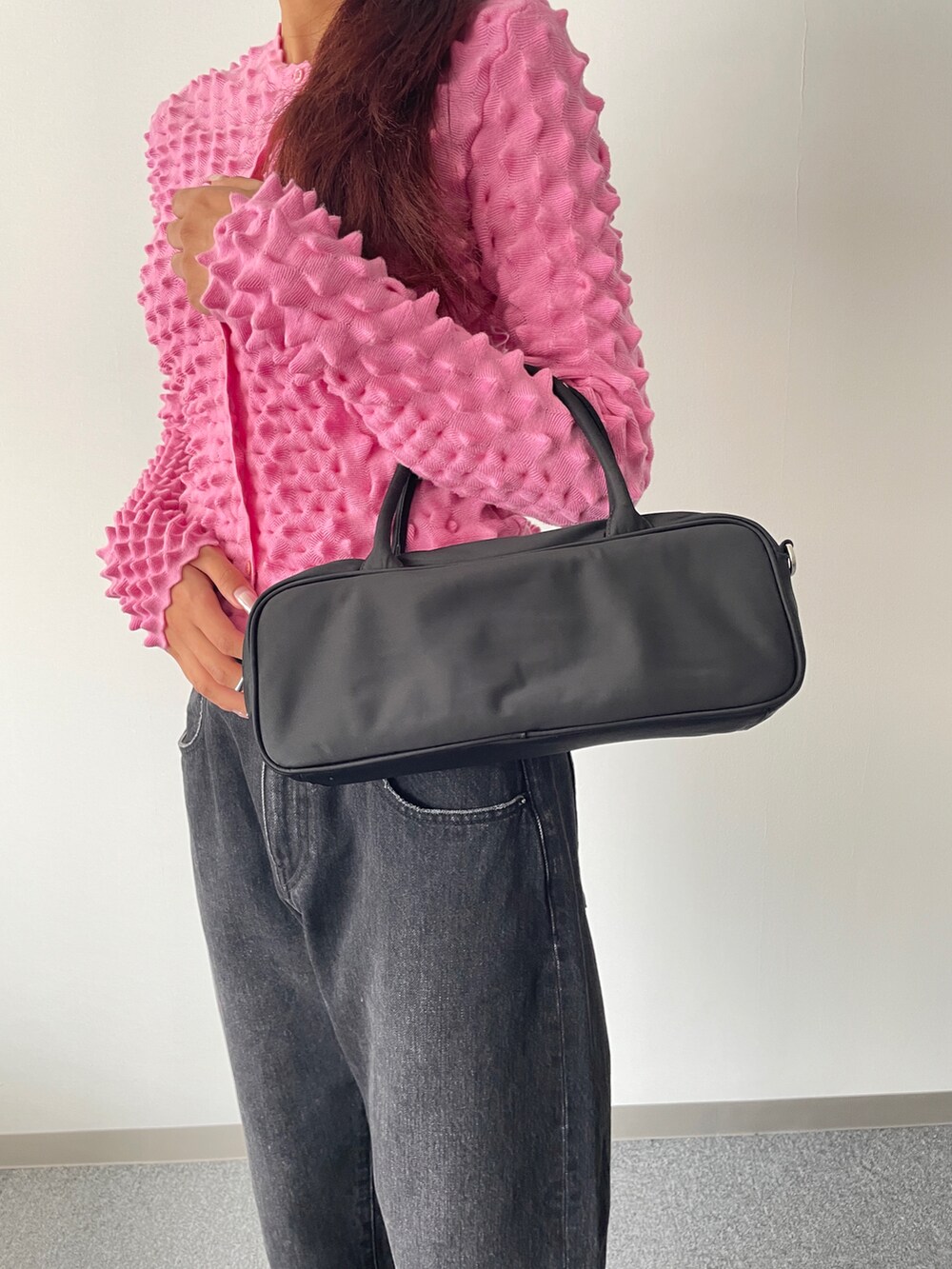 ブラック系のデニムパンツ、ピンク系のニット/セーター、ブラック系のショルダーバッグを着用したレディースの秋コーディネートの2枚目の写真