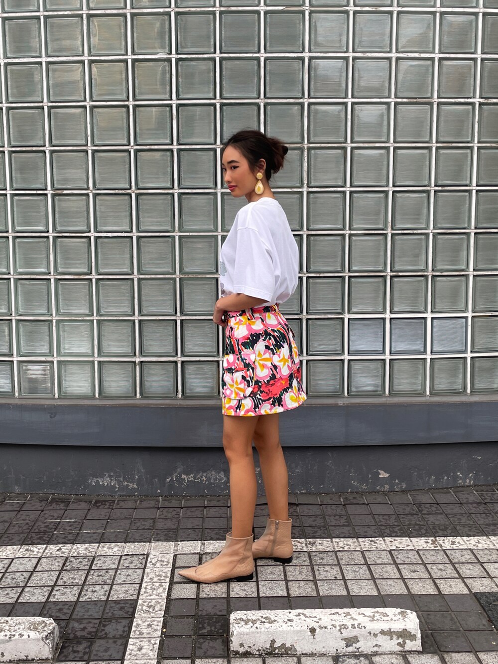 ホワイト系のトップス、ピンク系のスカート、ブラウン系のサンダルを着用したレディースの春コーディネートの2枚目の写真