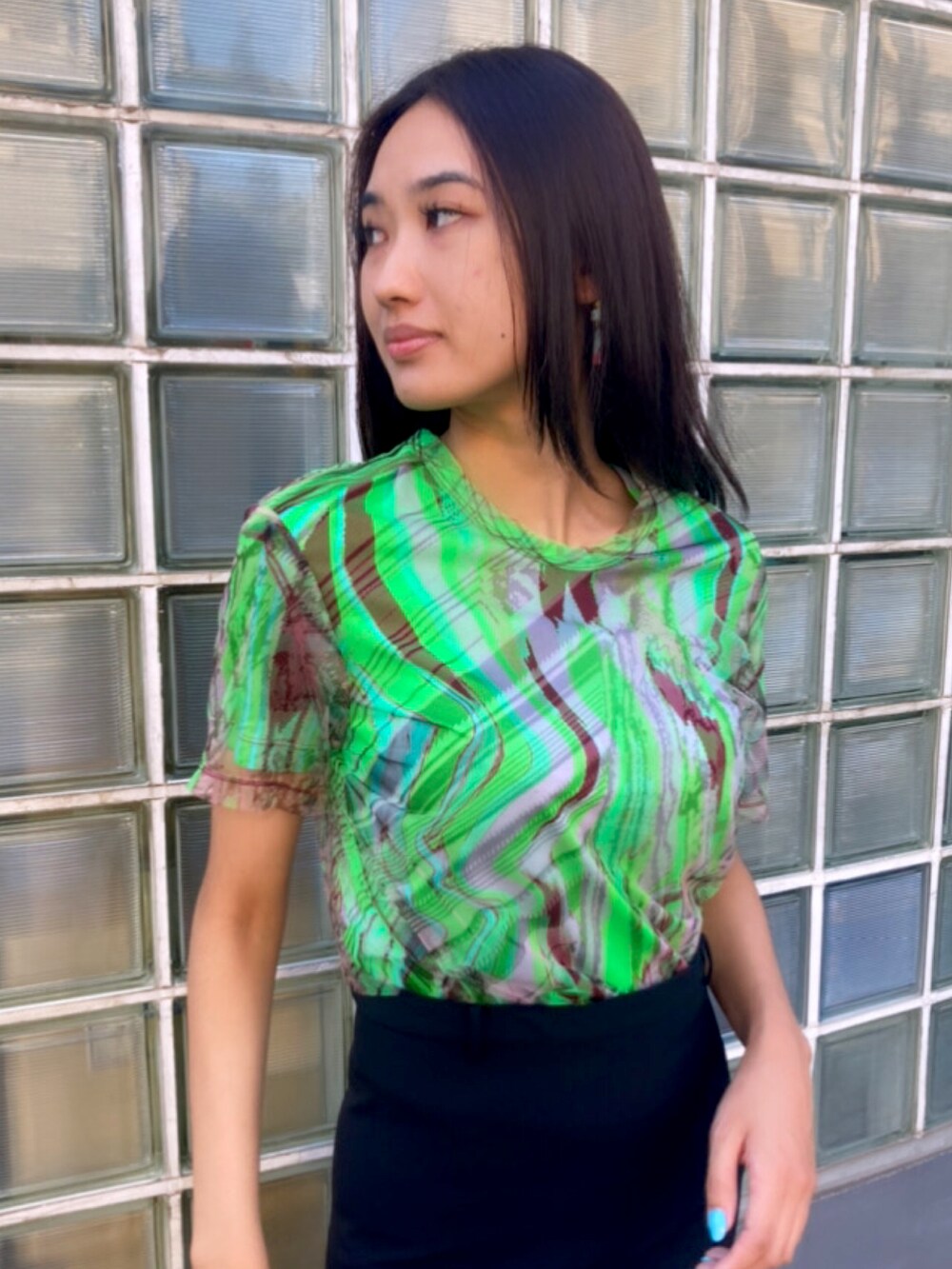 グリーン系のTシャツ/カットソー、ブラック系のスカートを着用したレディースの夏コーディネートの3枚目の写真