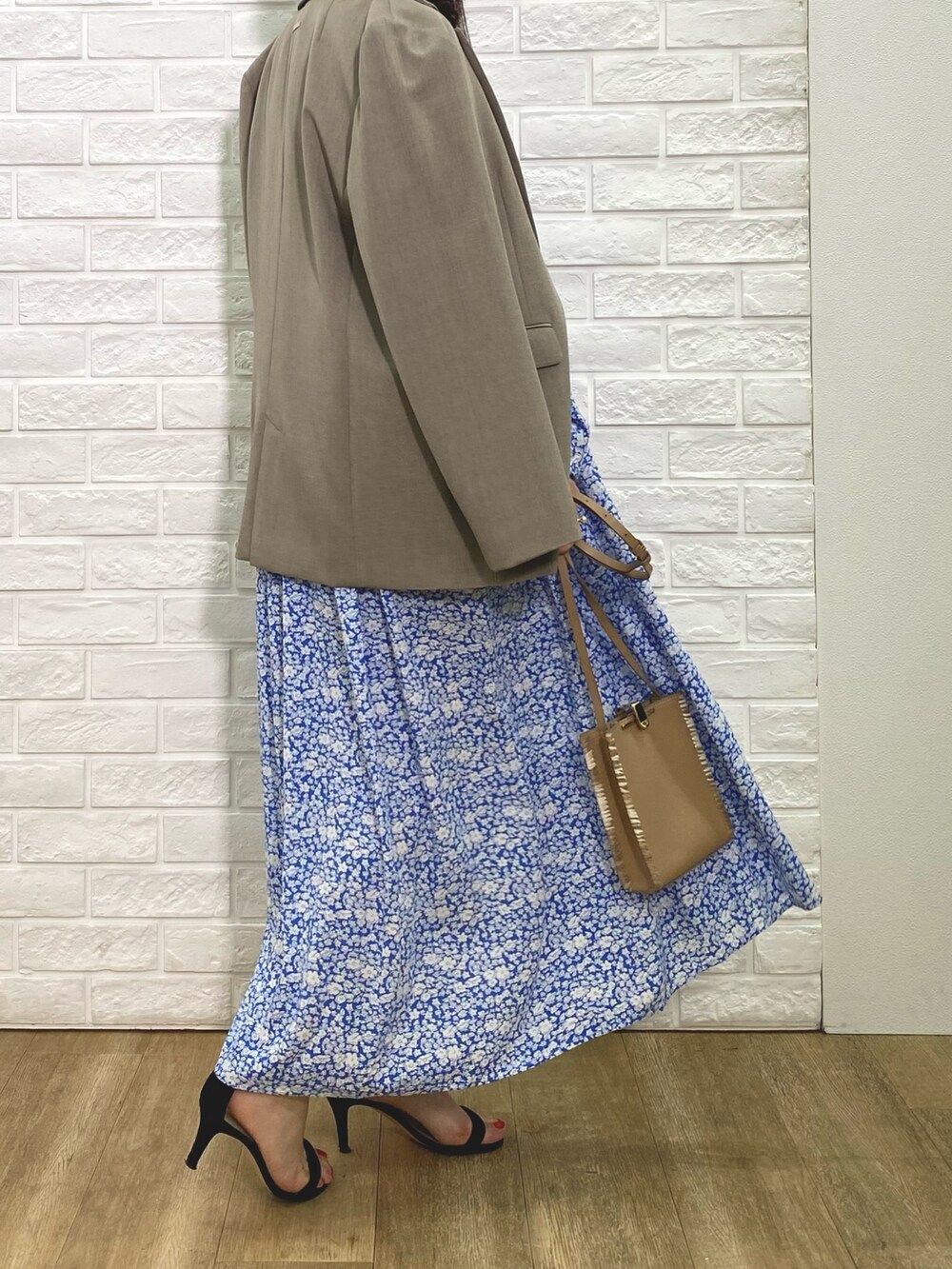 ベージュ系のテーラードジャケット、ブルー系のワンピース、ベージュ系のショルダーバッグを着用したレディースの冬コーディネートの2枚目の写真