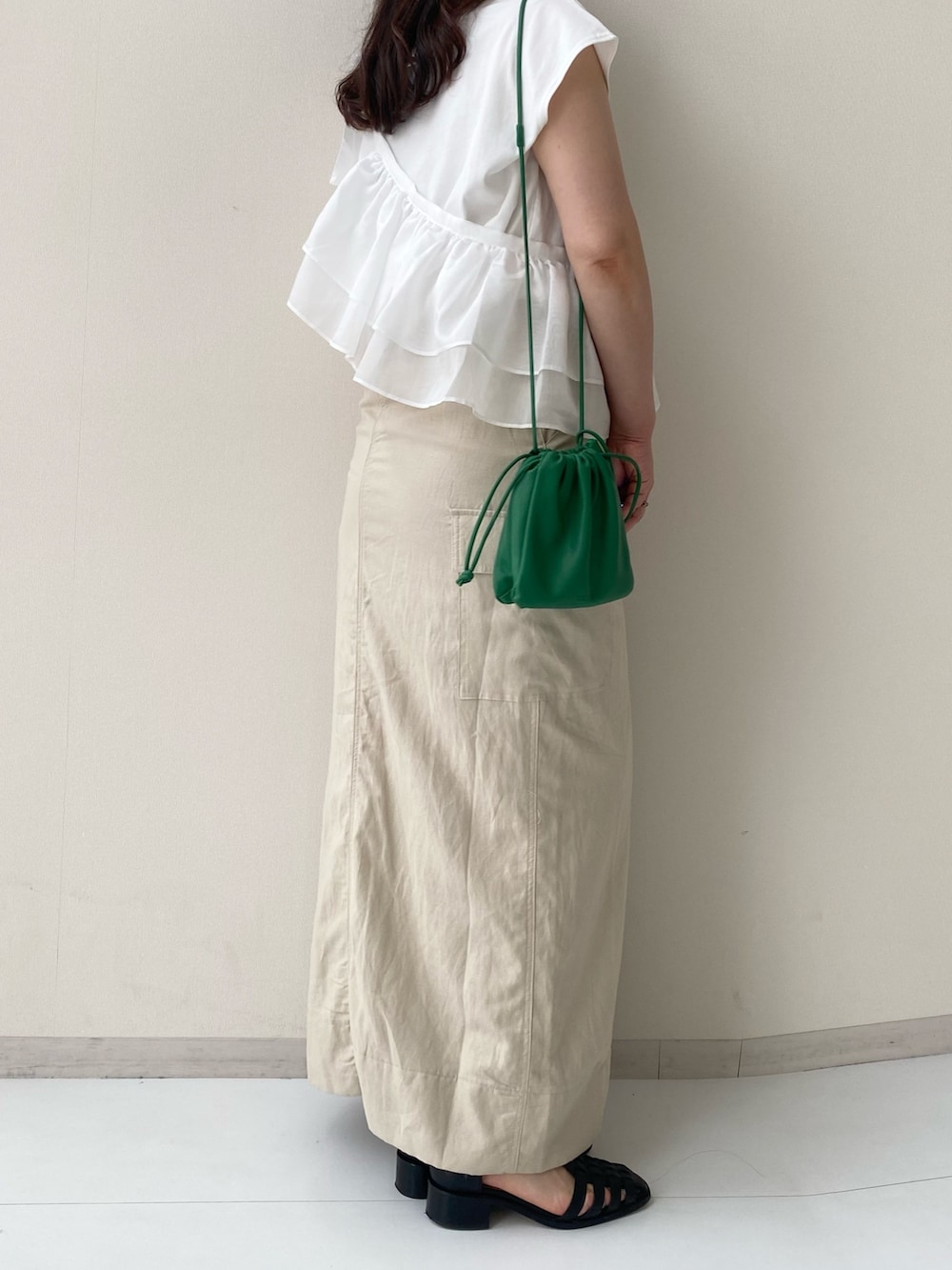 ホワイト系のTシャツ/カットソー、ベージュ系のスカート、ブラック系のサンダルを着用したレディースの夏コーディネートの2枚目の写真