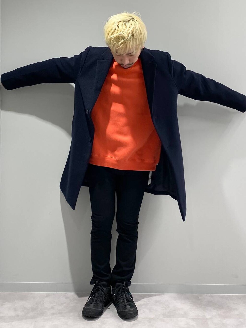 ブラック系のその他パンツ、ブルー系のチェスターコート、オレンジ系のスウェットを着用したメンズの冬コーディネートの5枚目の写真