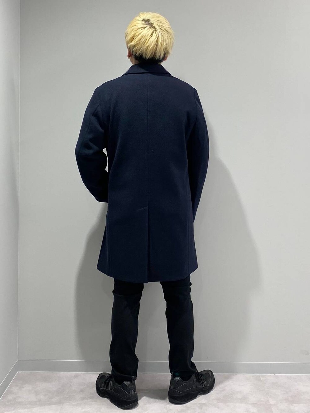 ブラック系のその他パンツ、ブルー系のチェスターコート、オレンジ系のスウェットを着用したメンズの冬コーディネートの3枚目の写真