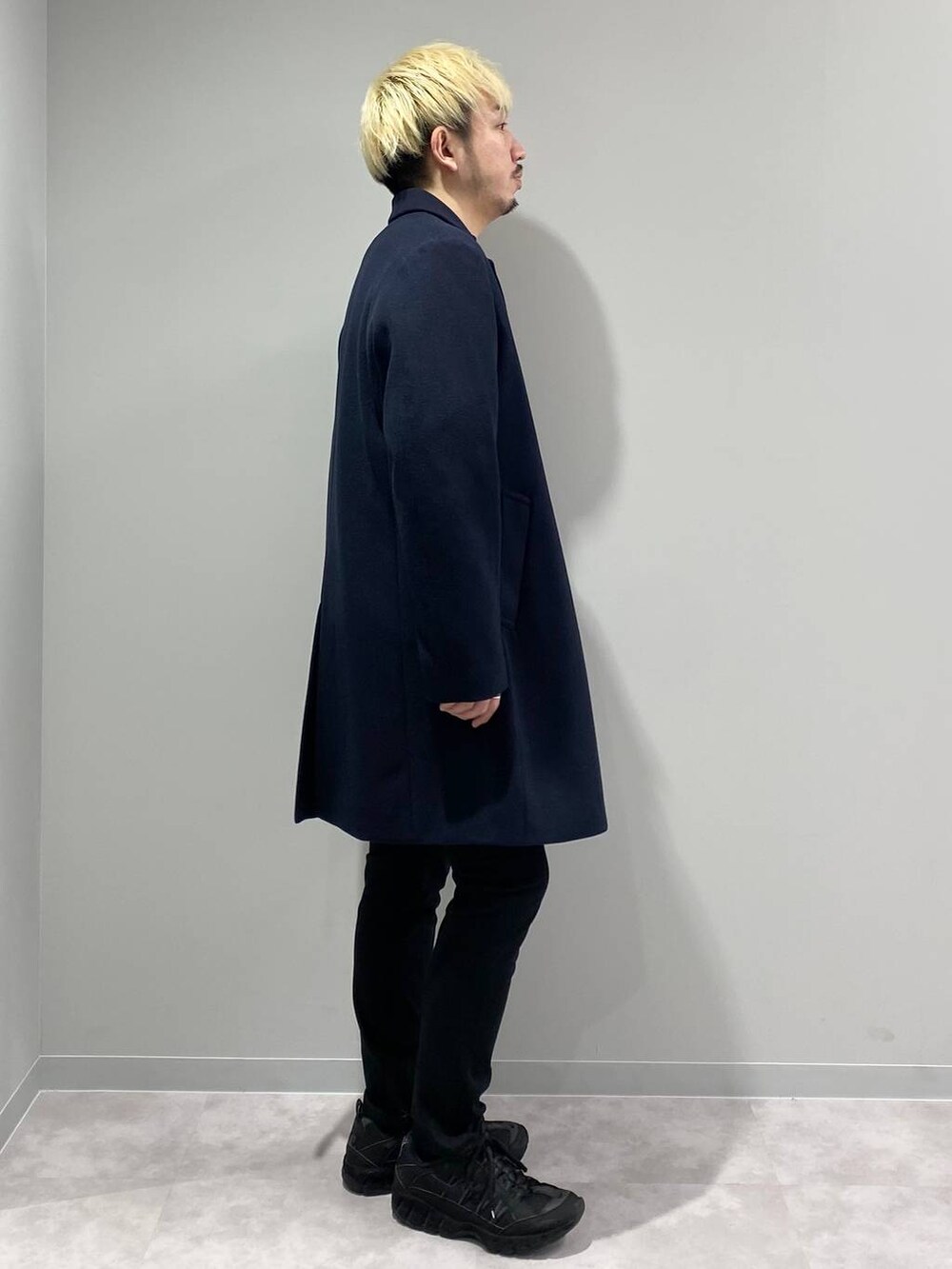 ブラック系のその他パンツ、ブルー系のチェスターコート、オレンジ系のスウェットを着用したメンズの冬コーディネートの4枚目の写真